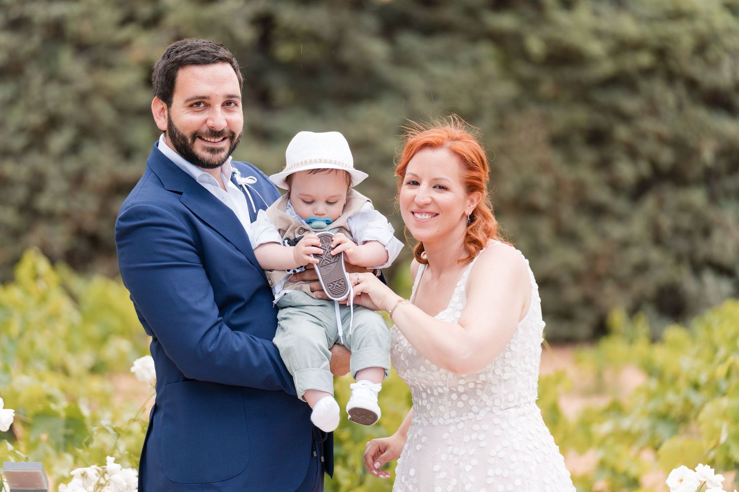 A couple and their baby share a tender moment during an outdoor family photo session in a scenic park setting.