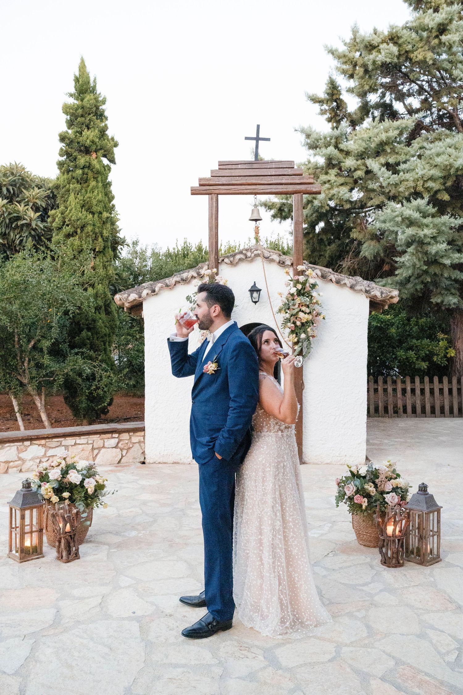 A romantic outdoor wedding shoot at a rustic white chapel with lanterns and floral arrangements.