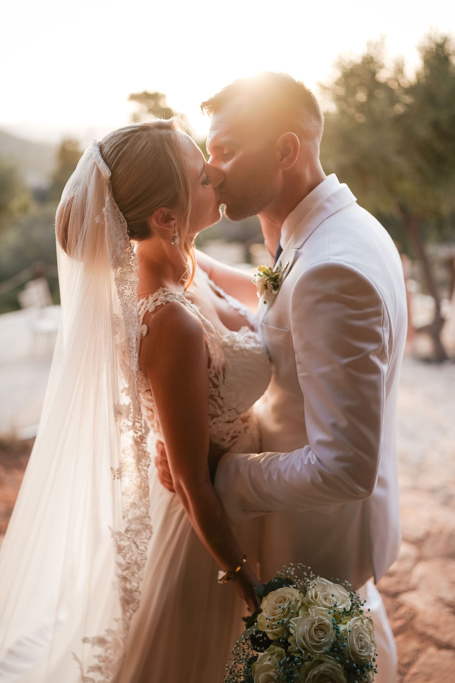 Romantic sunset wedding portraits with glowing backlight and flowing veil.
