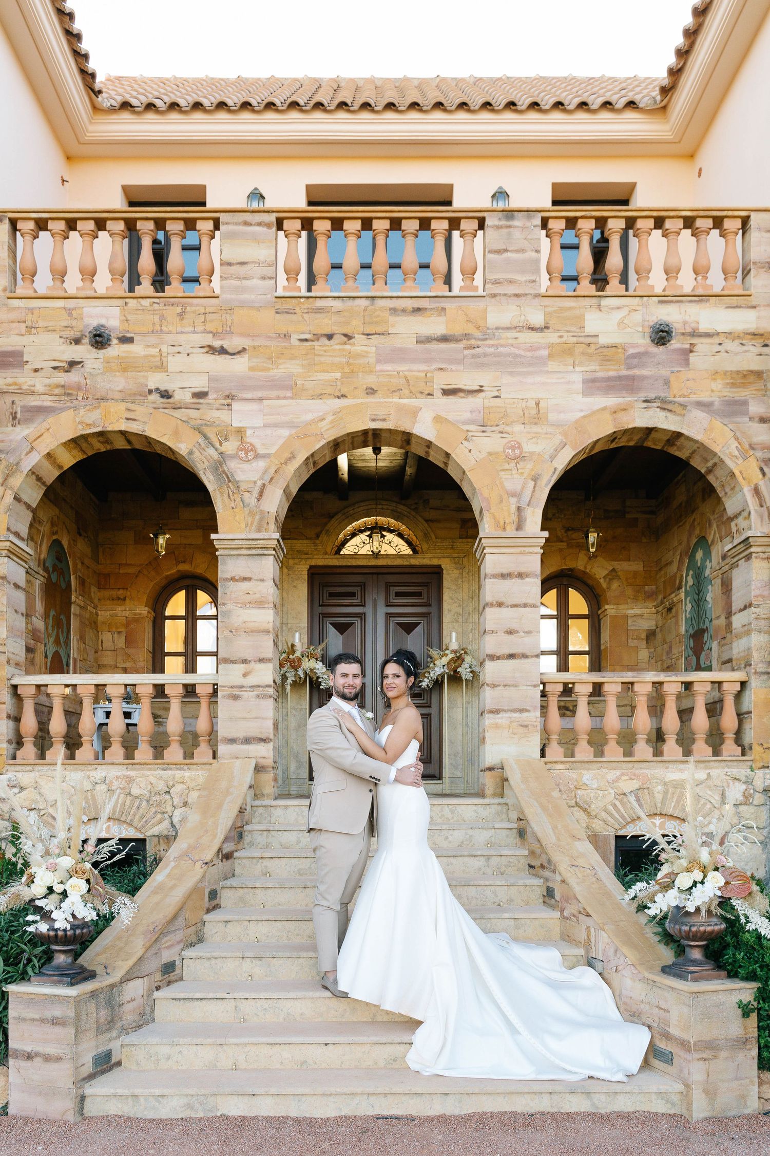 Elegant wedding photos taken at a traditional stone balcony with ornate architectural elements and arched doorways.