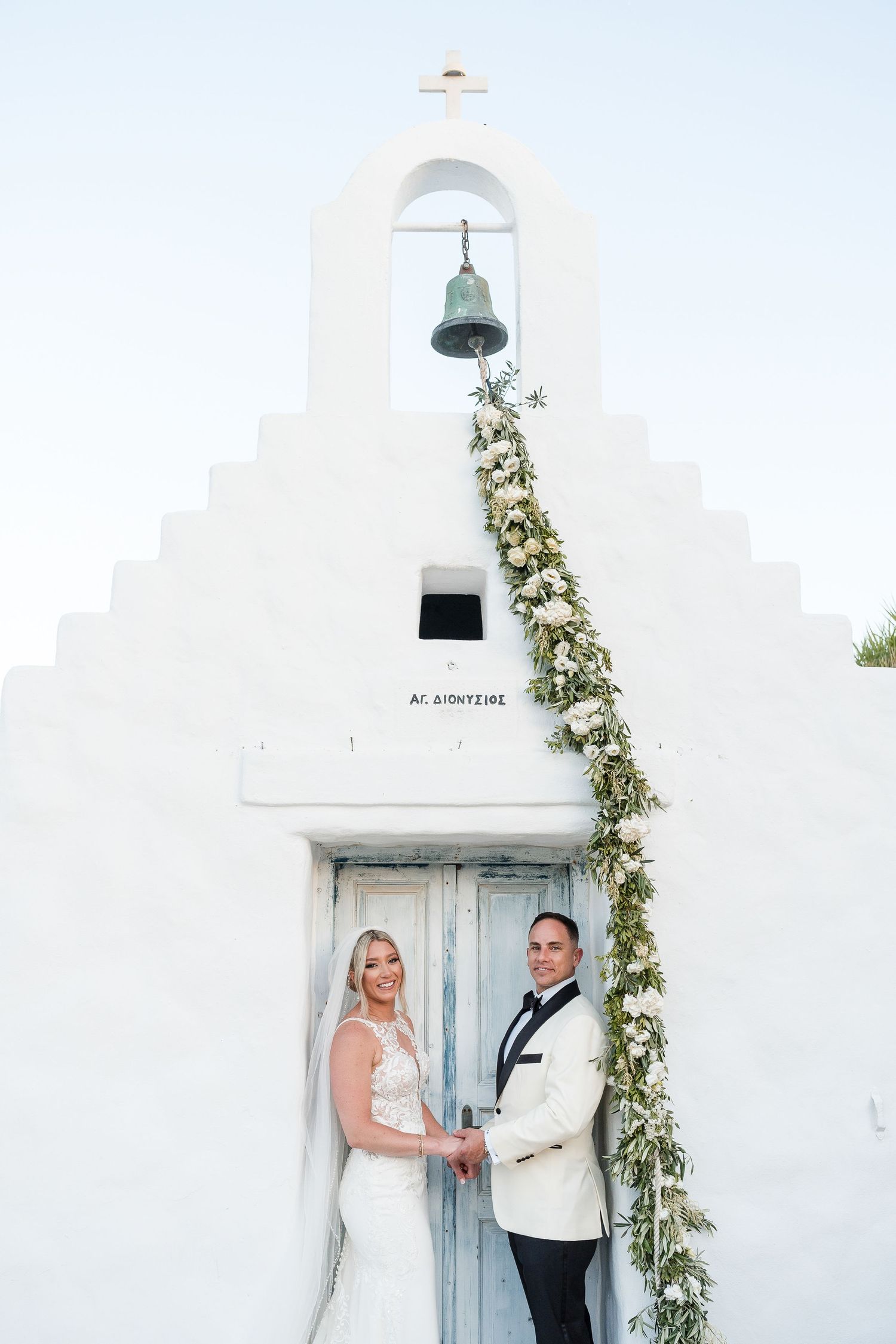White church chapel decorated with floral garlands creates an elegant wedding ceremony backdrop.