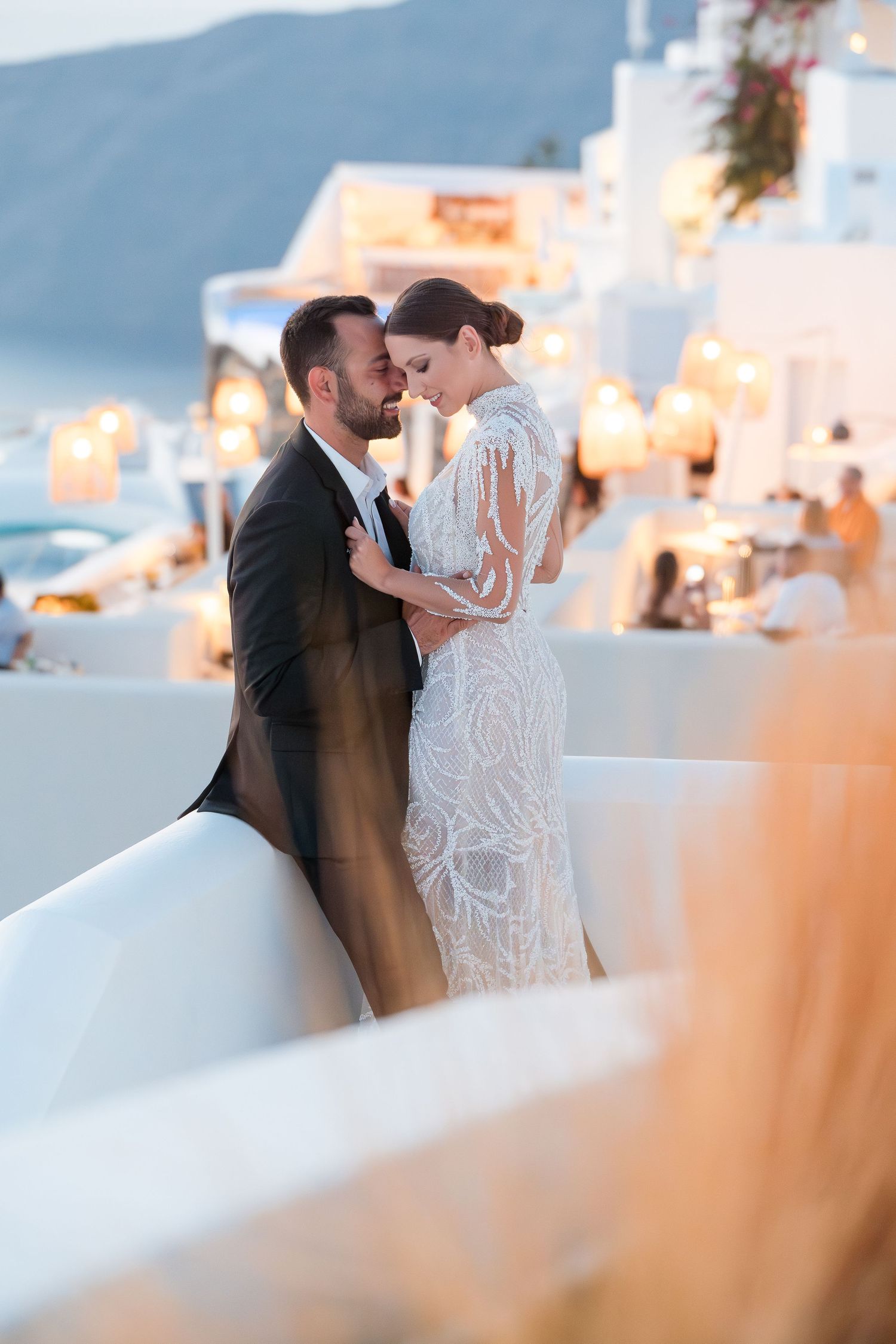 Romantic sunset wedding moment captured against whitewashed buildings in Santorini.
