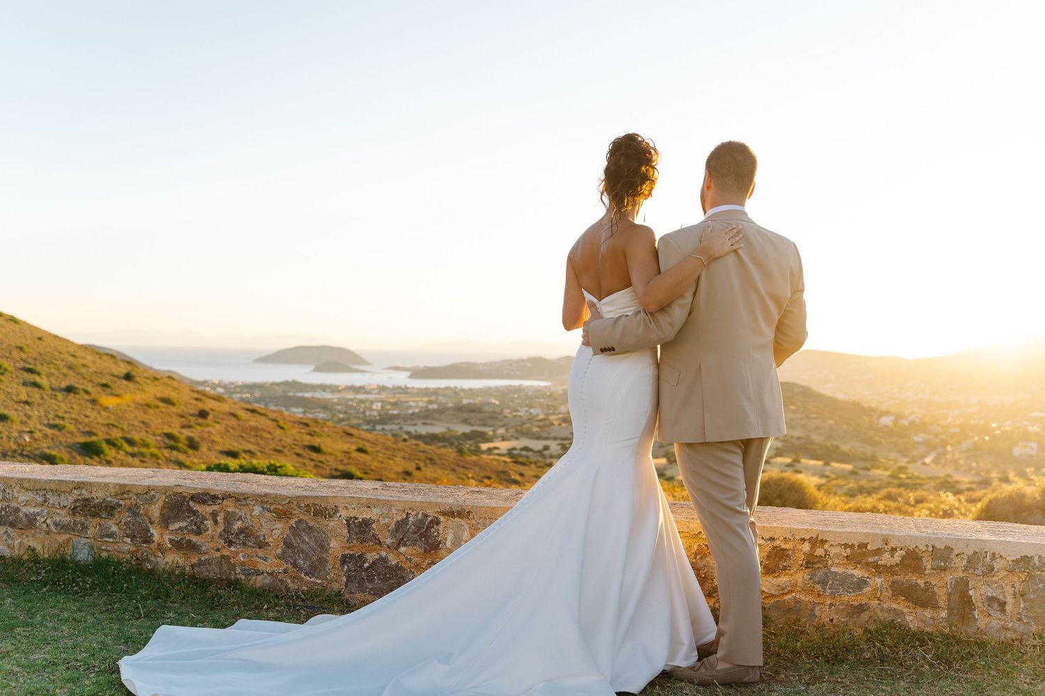 A romantic sunset moment with newlyweds overlooking a Mediterranean coastal landscape.