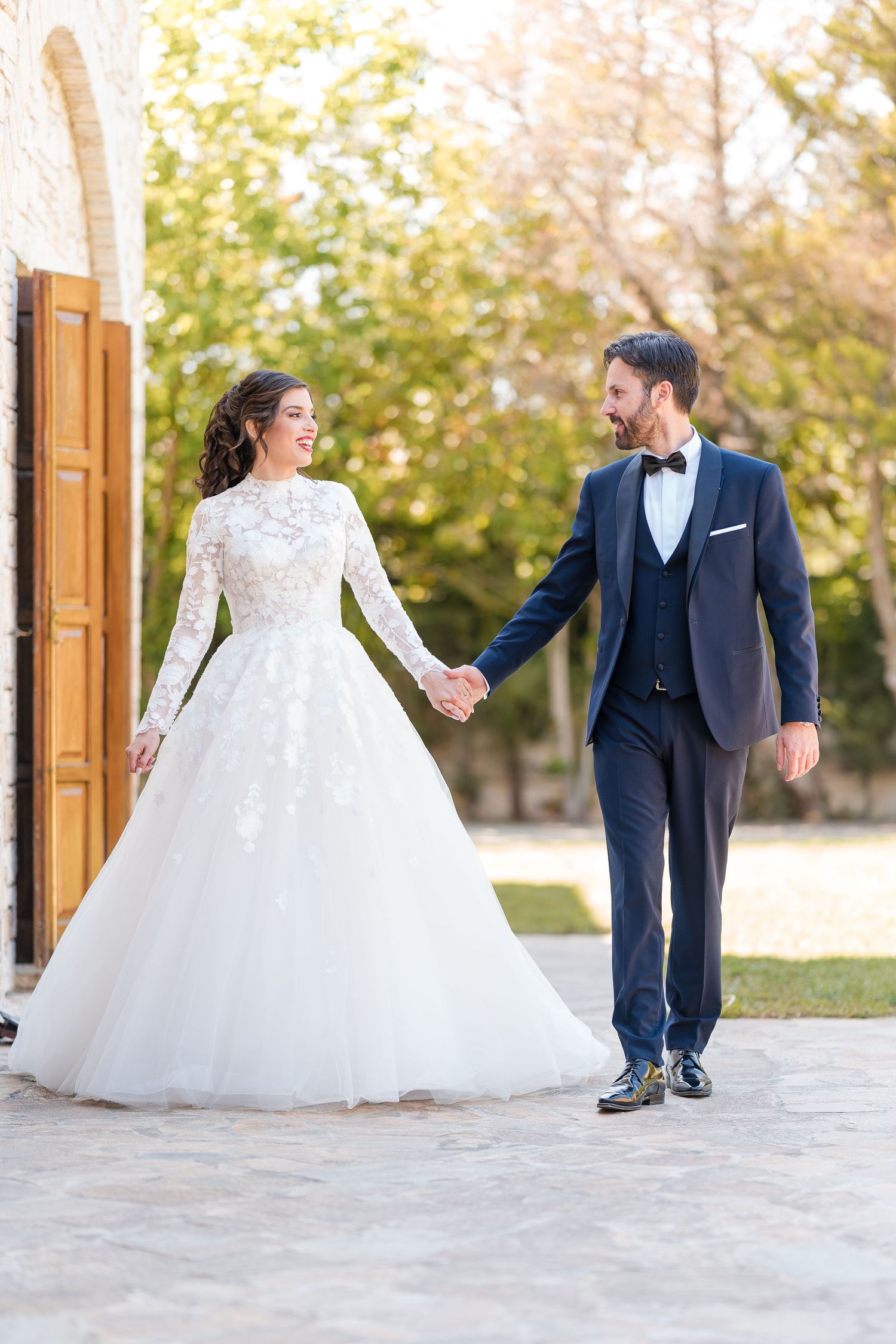 A wedding couple twirls and dances together, with the bride's white gown flowing gracefully on a light stone terrace.