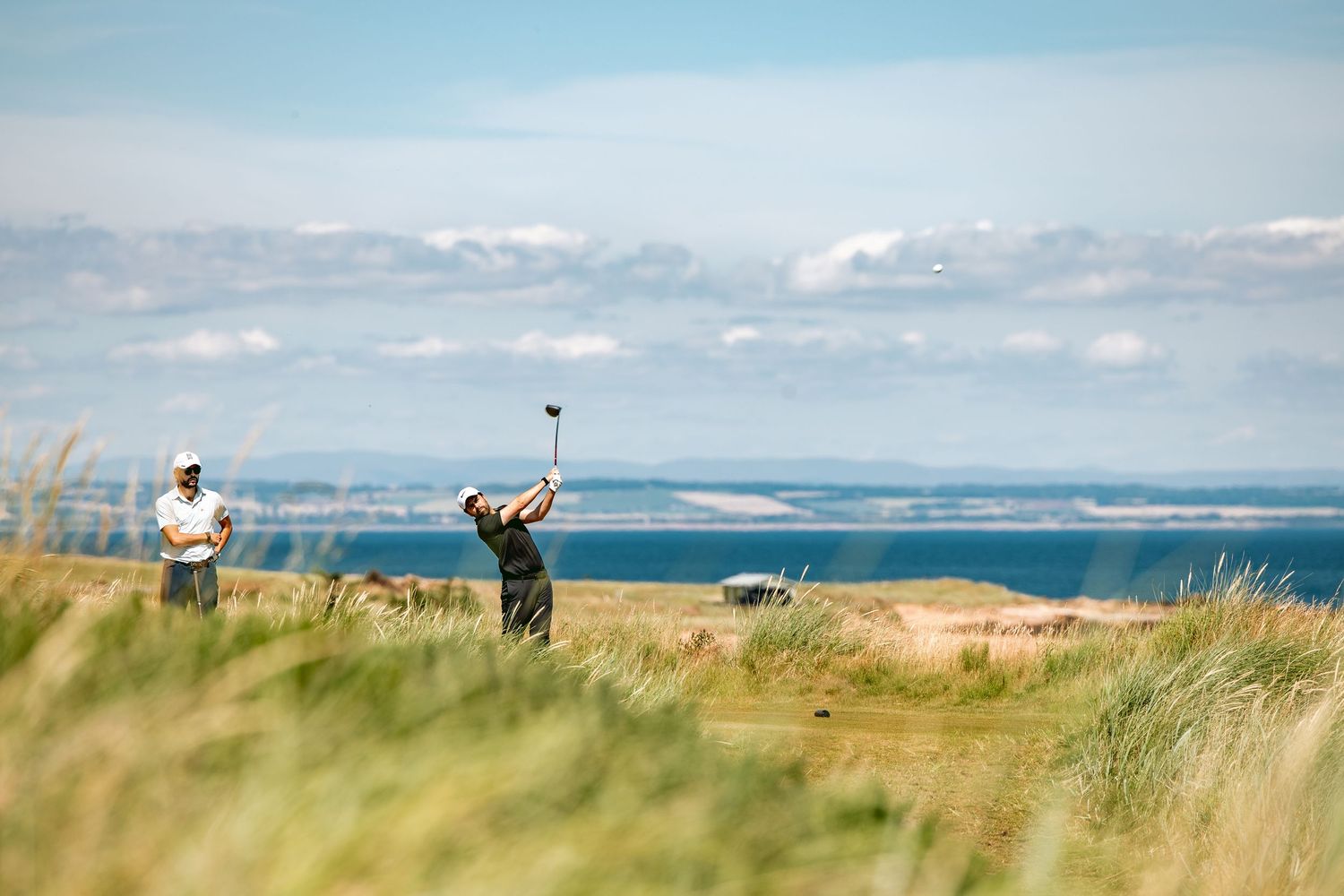 Golfers playing at golf course with one player in action