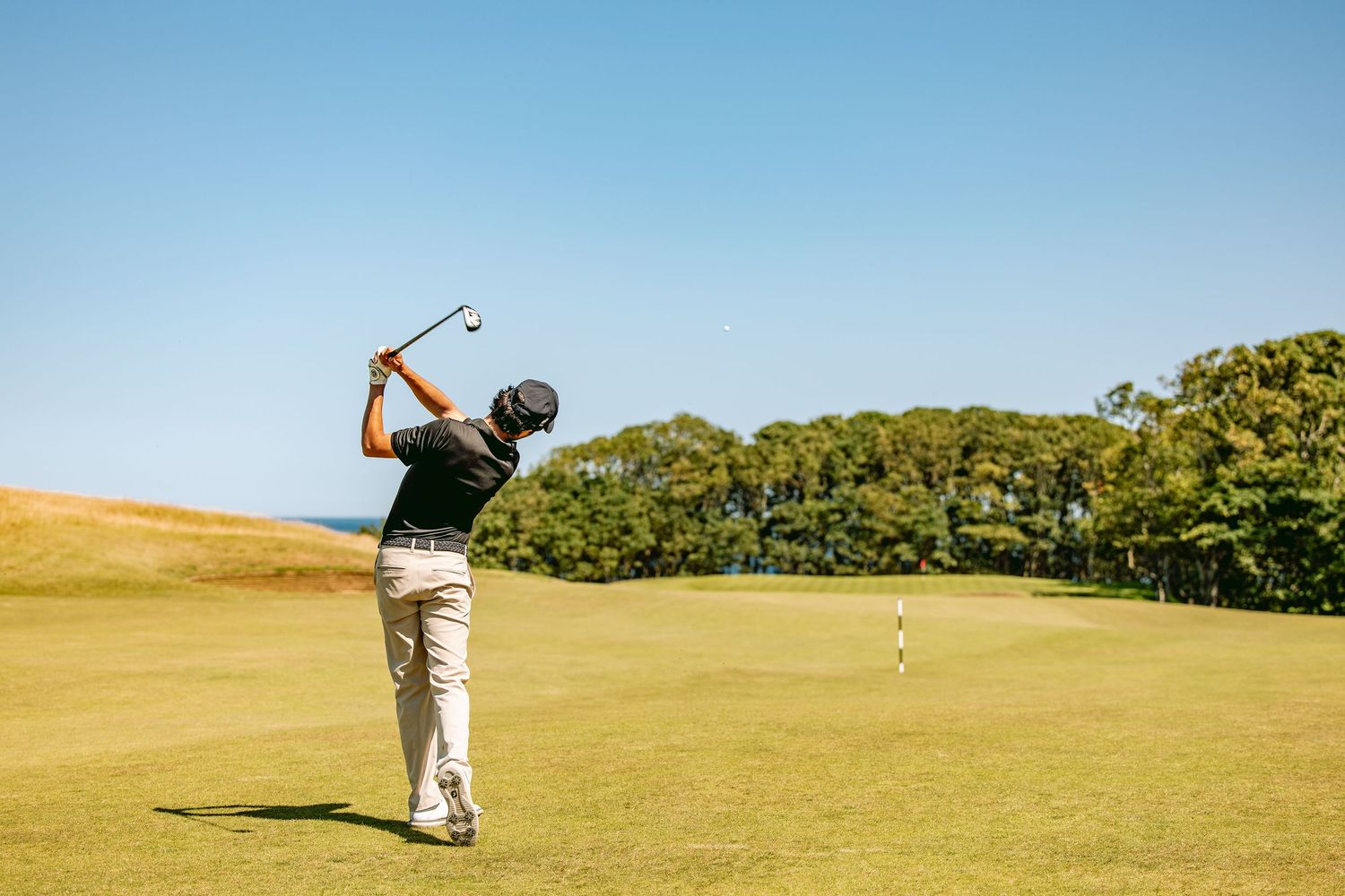 Golfer in grey pants playing a calculated shot on a sunny day at Kingsbarns Links.