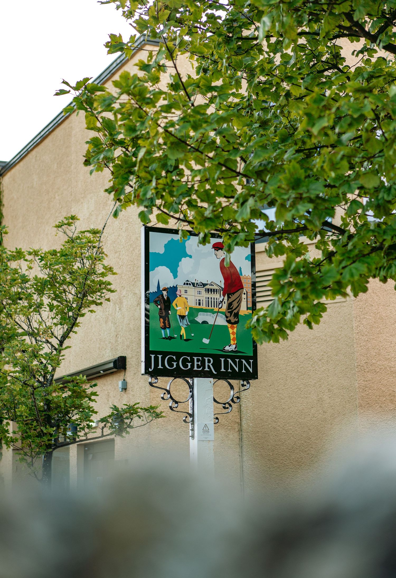 Old Course photo at The Jigger Inn spot with green tree branches visible above.