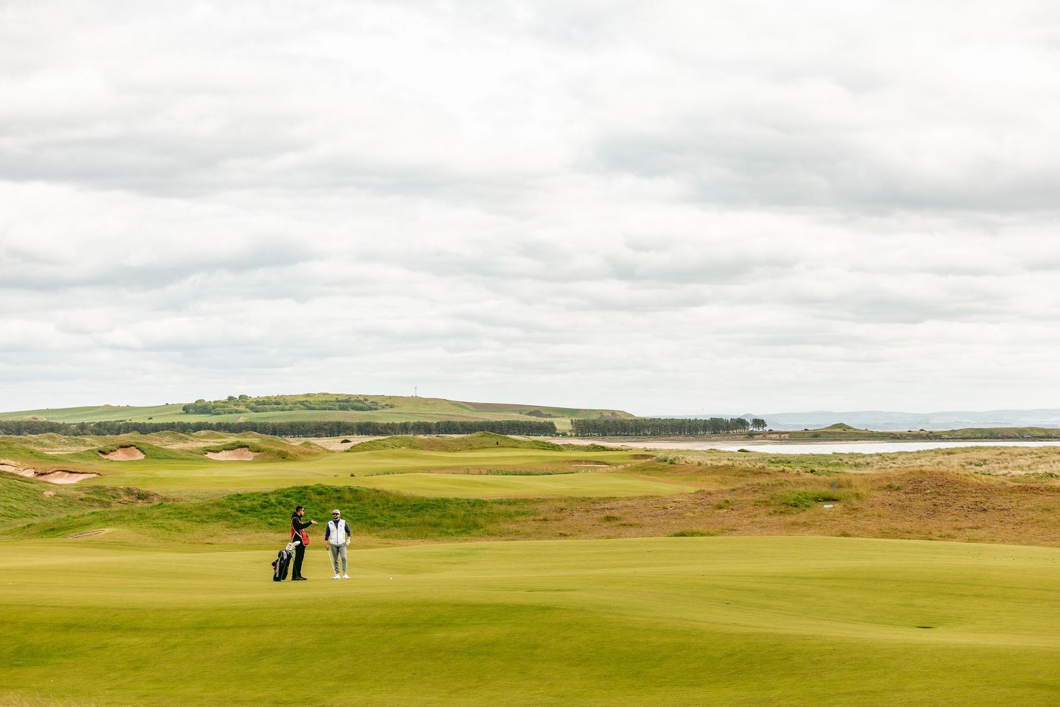 Far view of two golfers standing at Dumbarnie Links.
