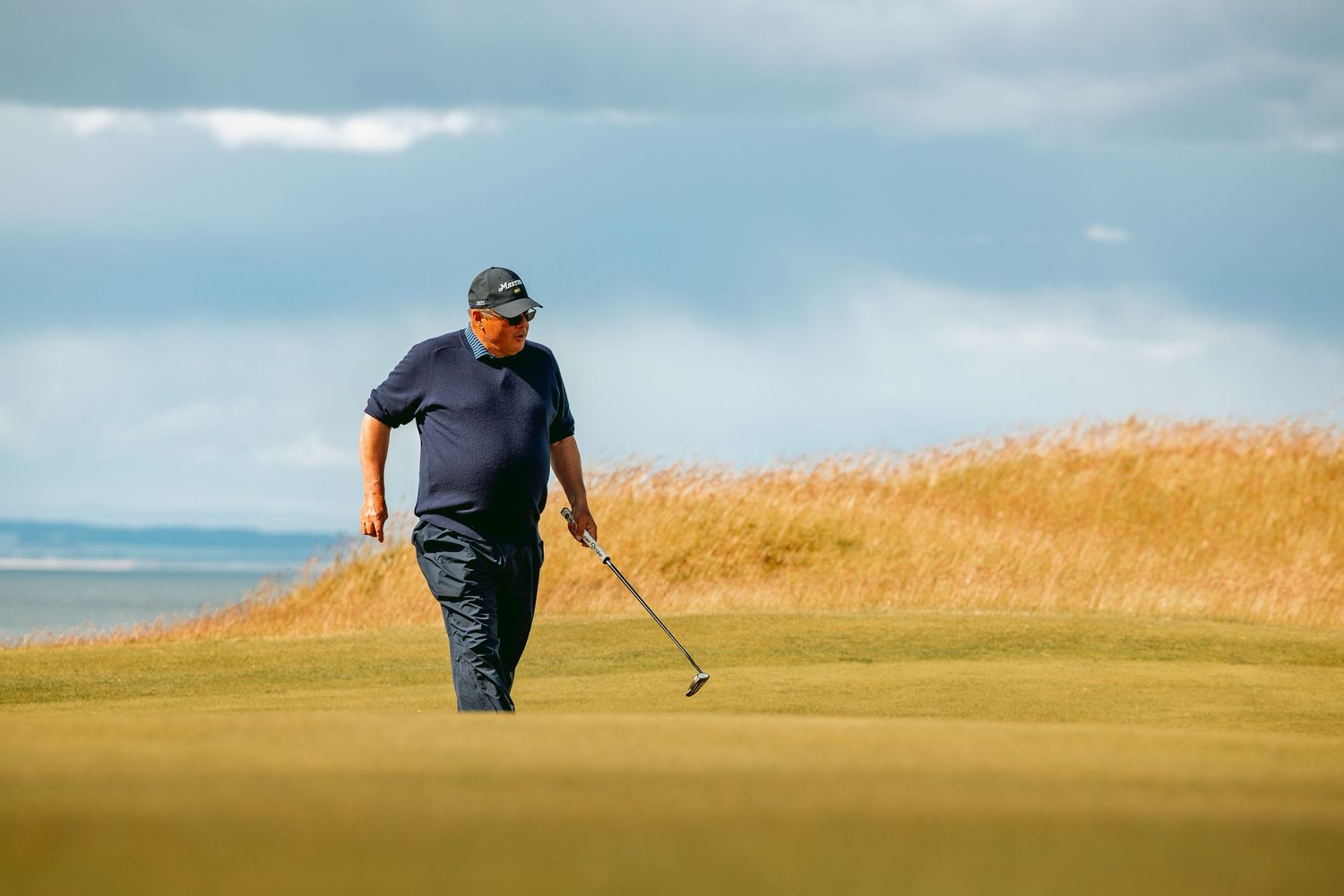 Golf player with golf club walking in action