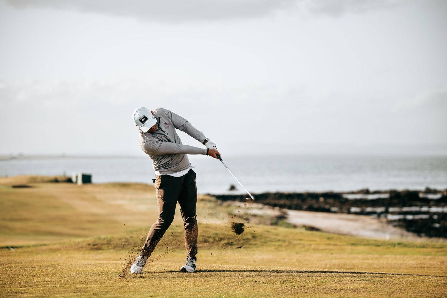 Golfer in action, swinging his golf club while playing at Crail Balcomie Links.
