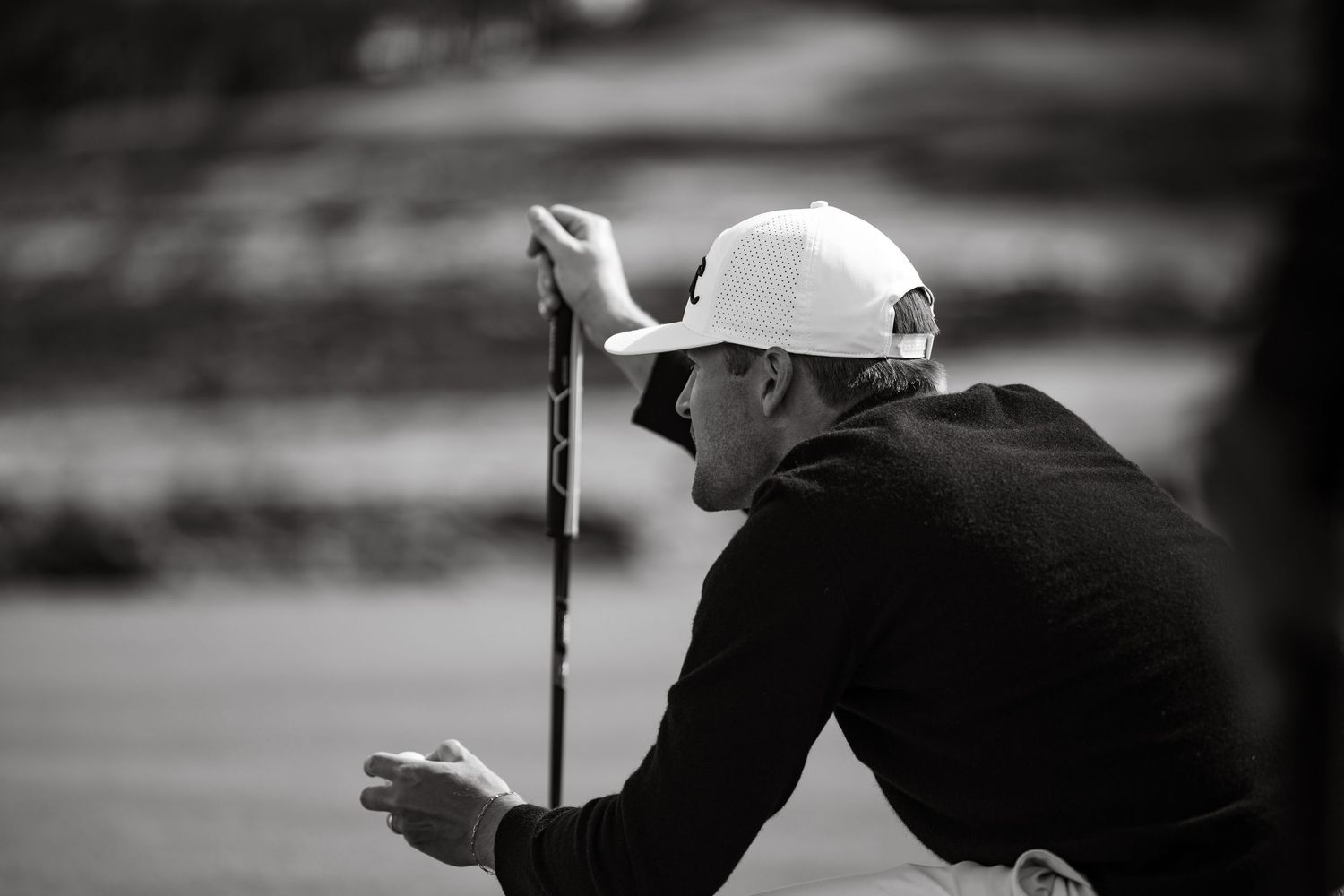 Golf player sitting in focused mood with golf ball and stick in hand