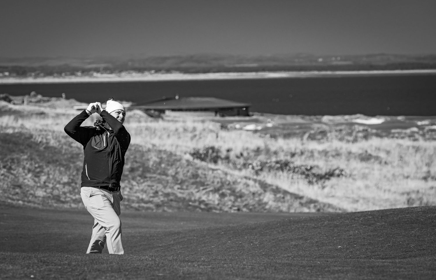A golfer playing golf in action with club in air.