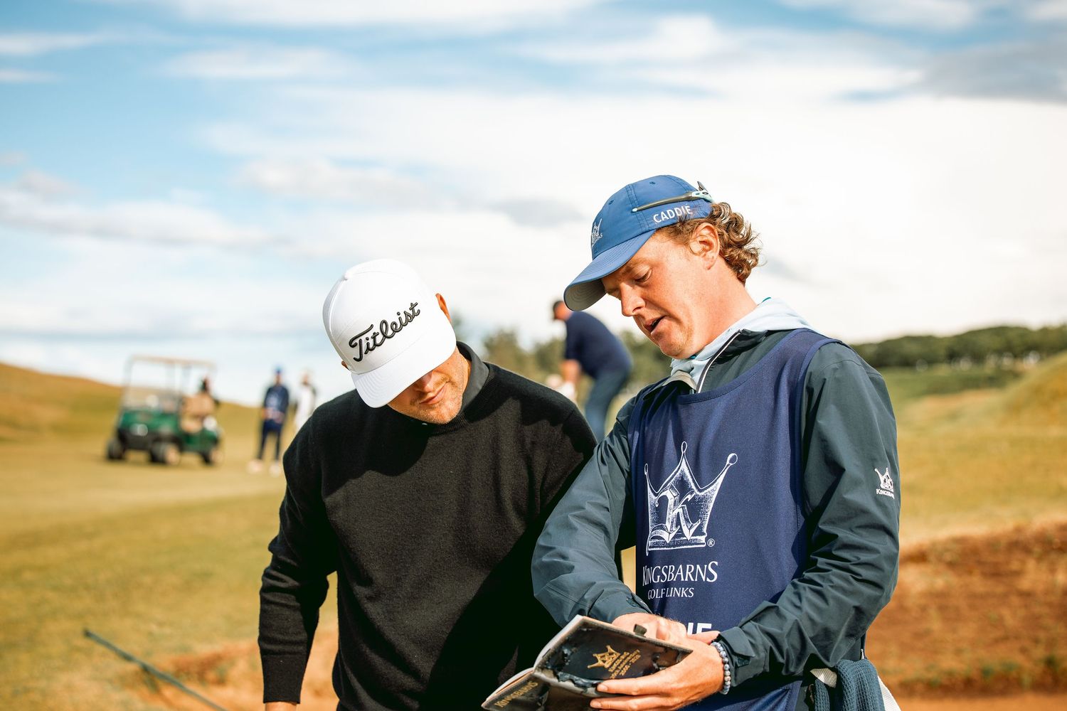 Kingsbarns crew showing guide book to a golfer