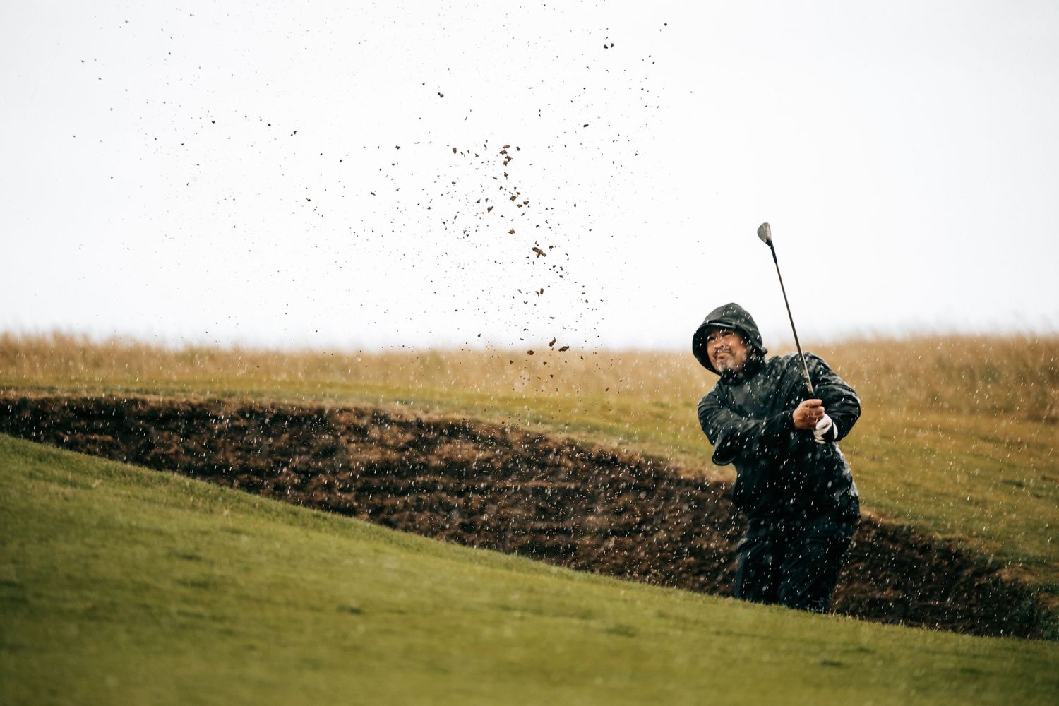 Golfer swings club to play shot at Kignsbarns golf course.