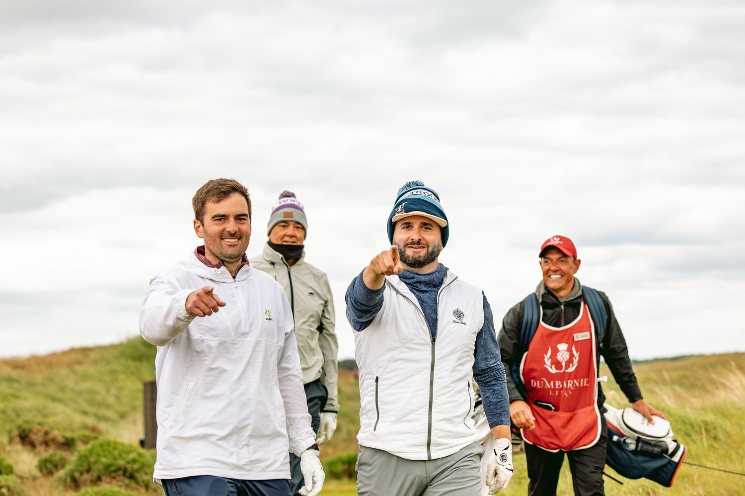 Golfers at Dumbarnie Links walking with fingers pointing at the camera.
