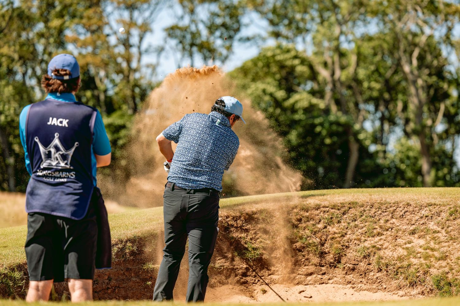 Golfer playing at Kingsbarns Links played a shot from bunker with sand flying.