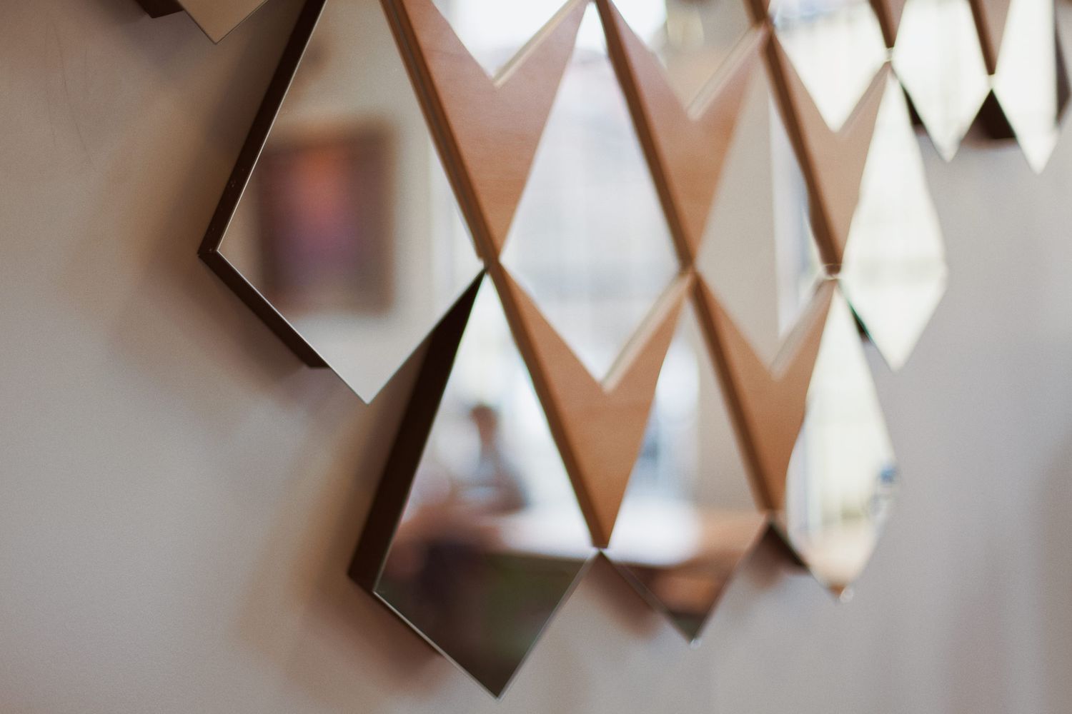 Geometric wall art installation with diamond-shaped panels in metallic and white colors creates a modern architectural pattern.