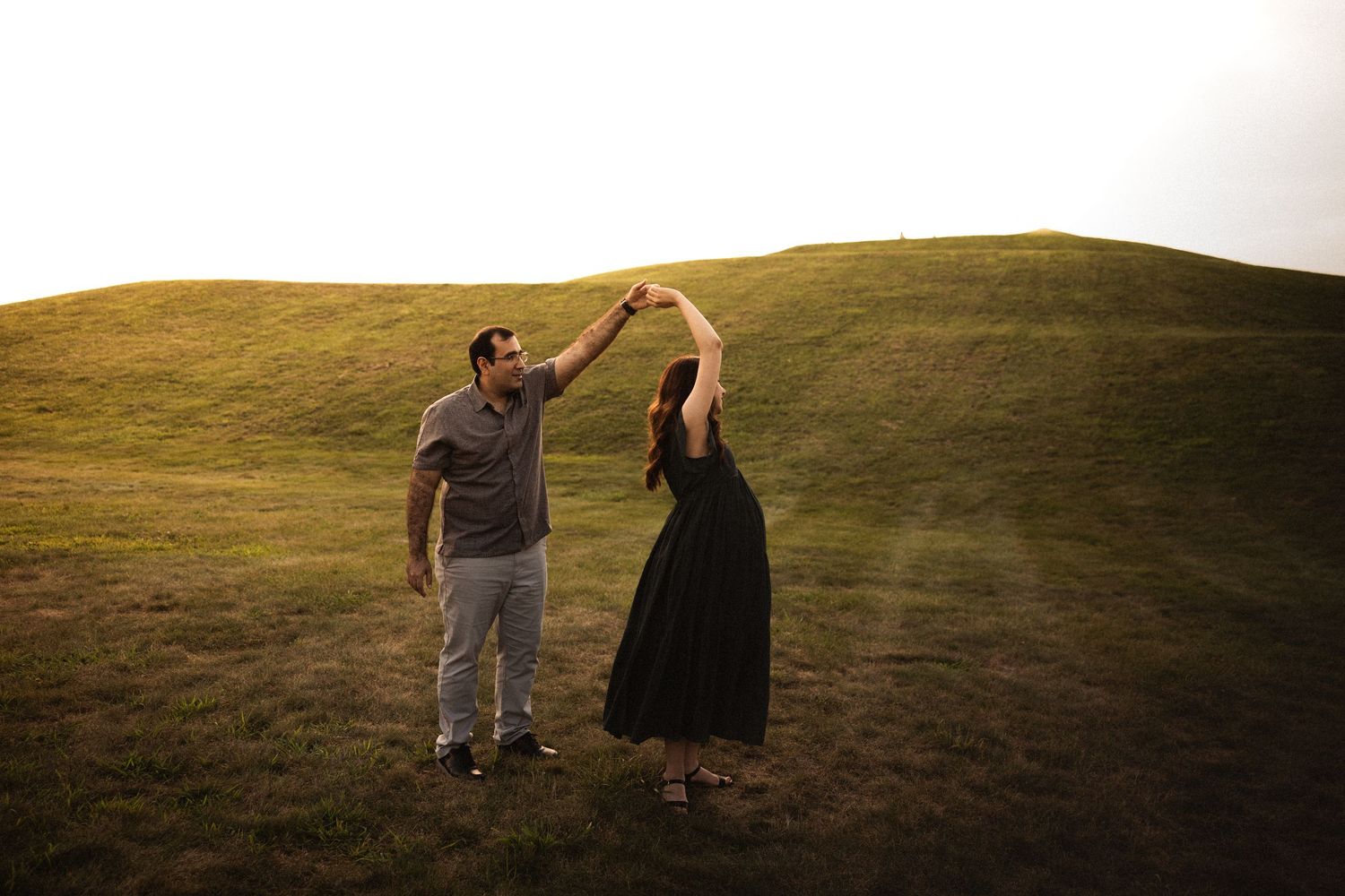 Couple walking hand in hand during sunset maternity photo session.