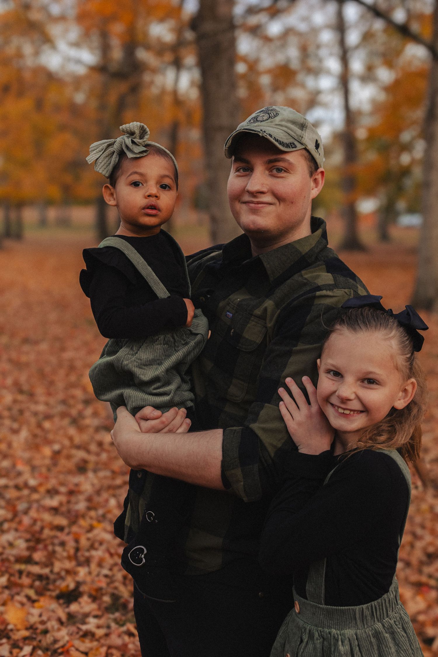 A fall family photoshoot in a forest filled with orange autumn leaves and warm golden light.