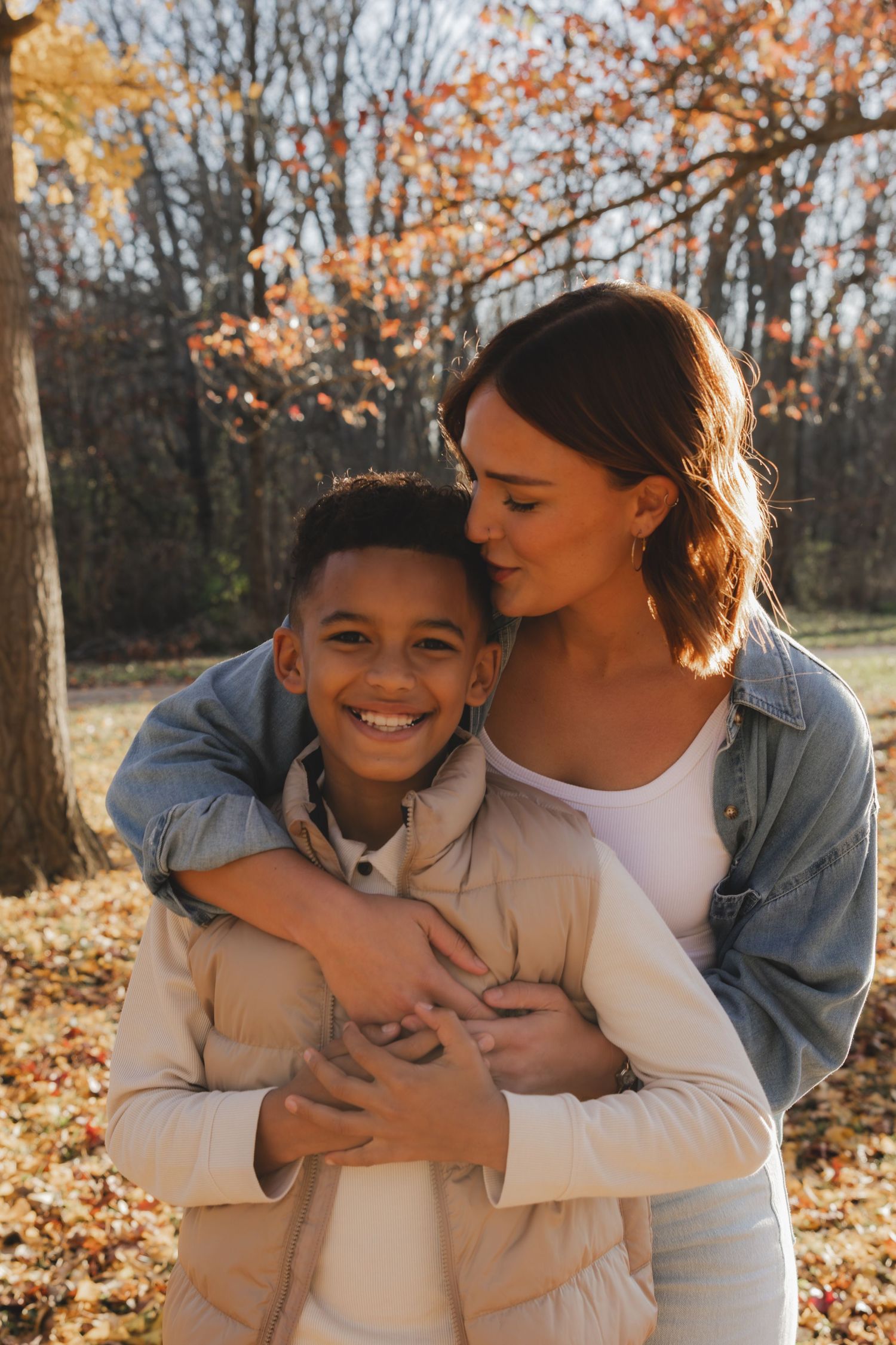 Mother and child sharing joyful embraces among fall foliage.