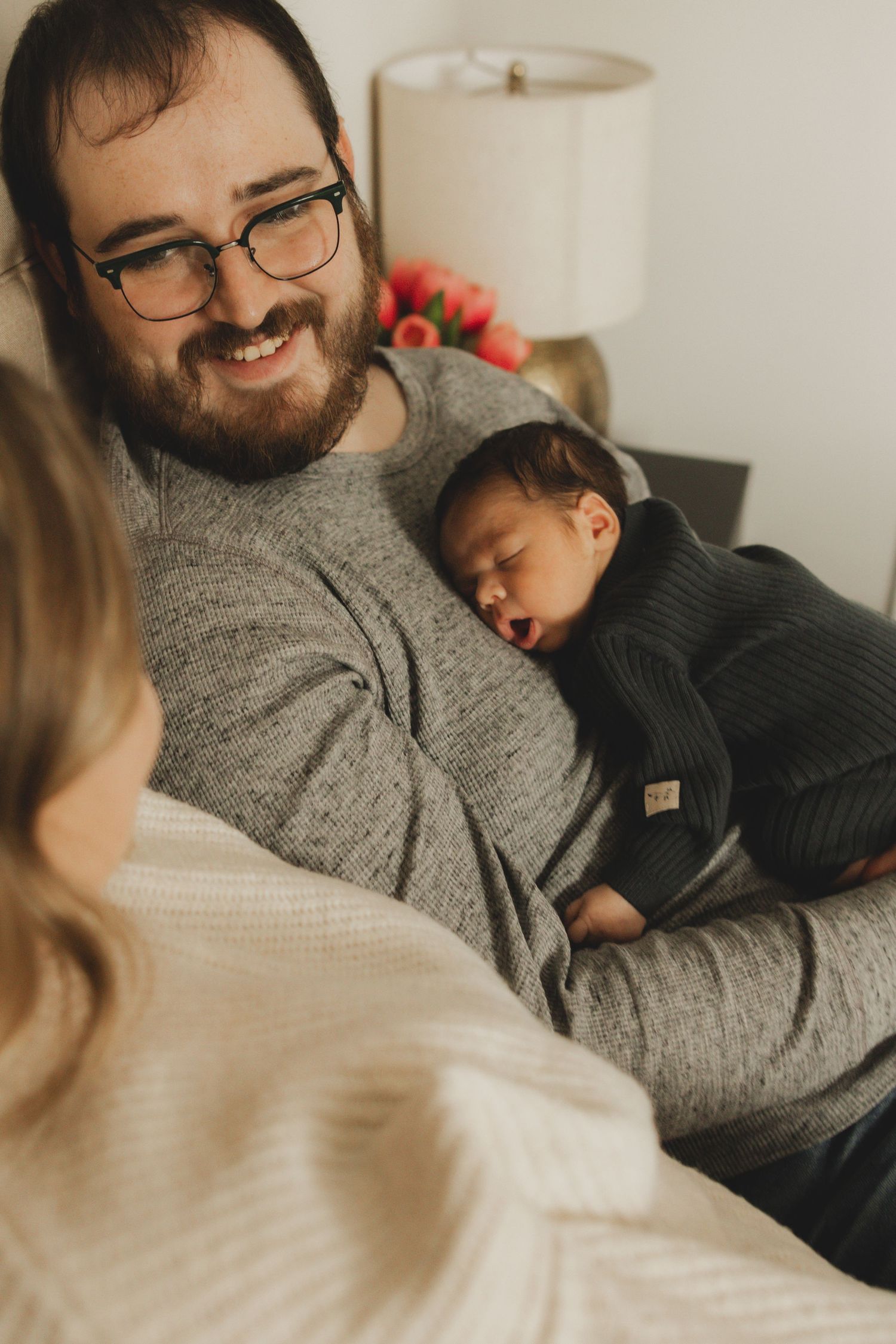 A tender moment of parent and child relaxing together on a couch in warm lighting.