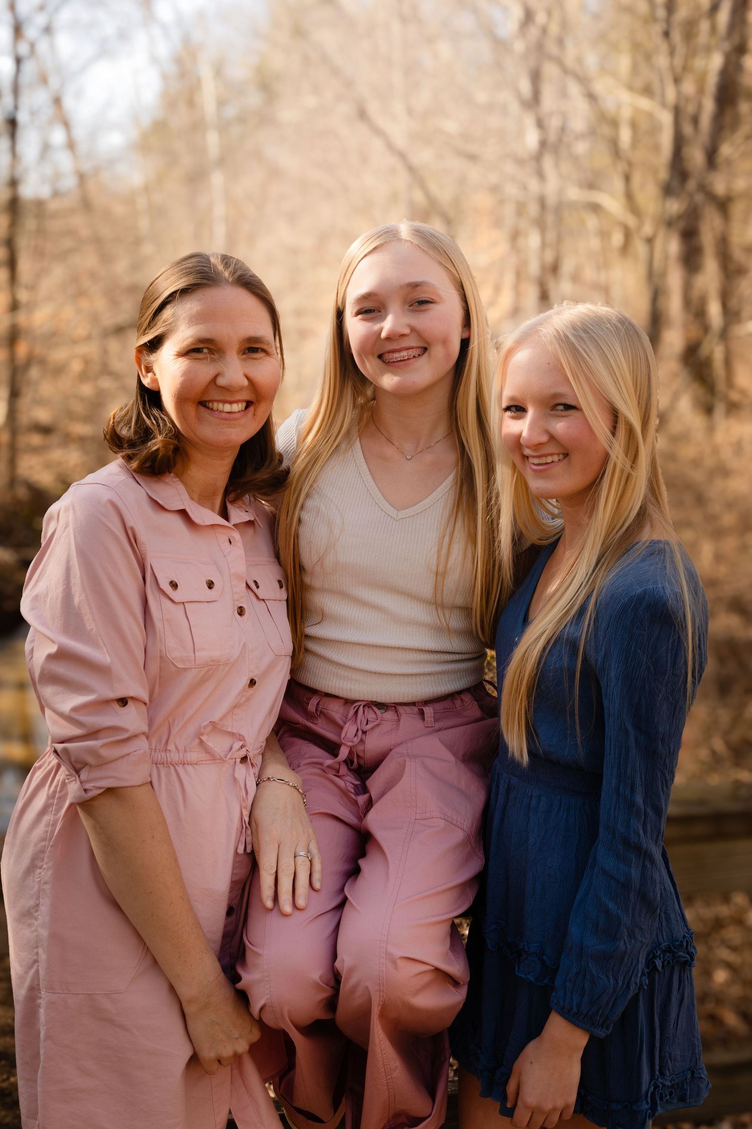 Group of young friends in pink and blue dresses smiling together outdoors.
