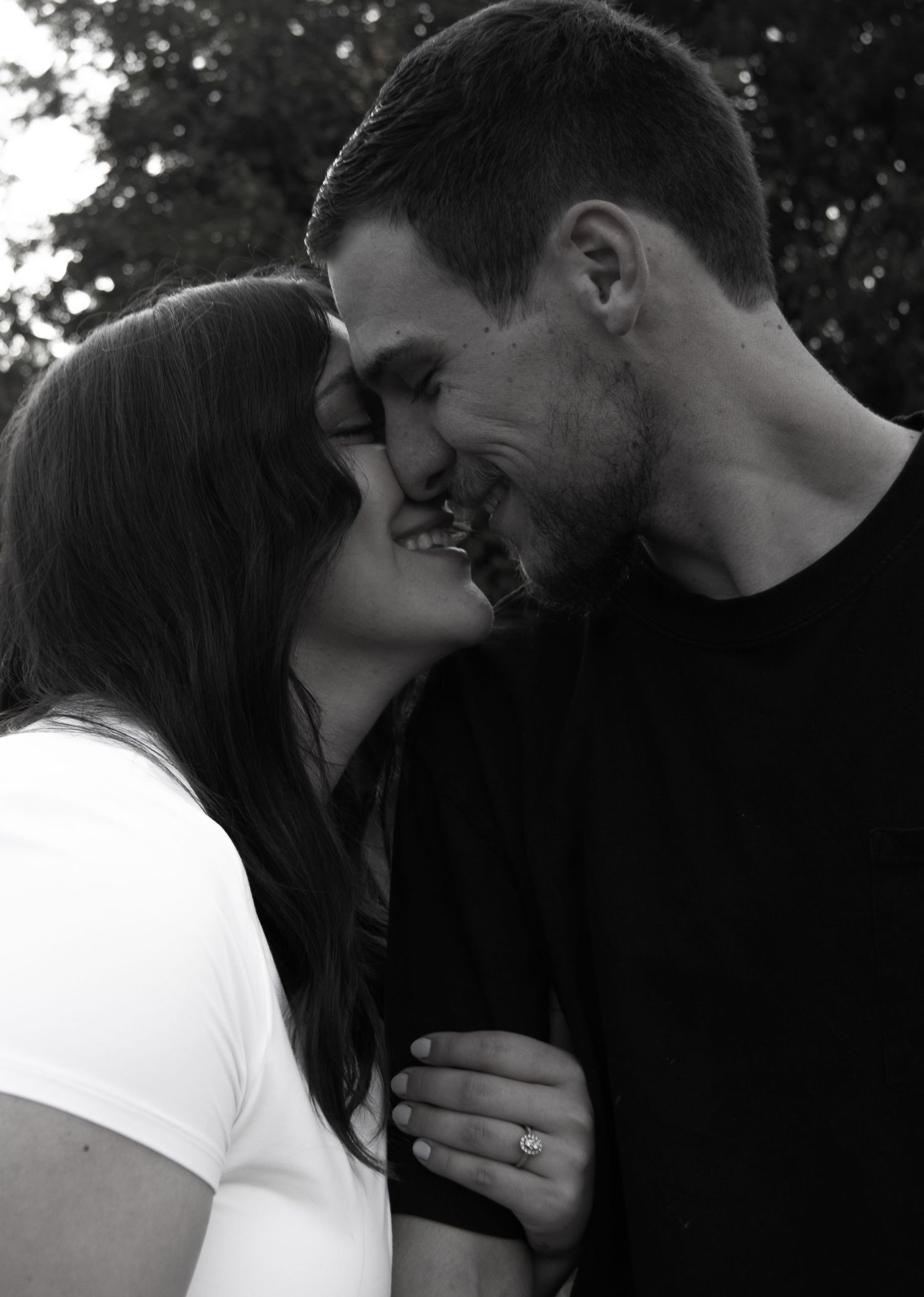 An intimate black and white portrait of a couple sharing a tender moment.