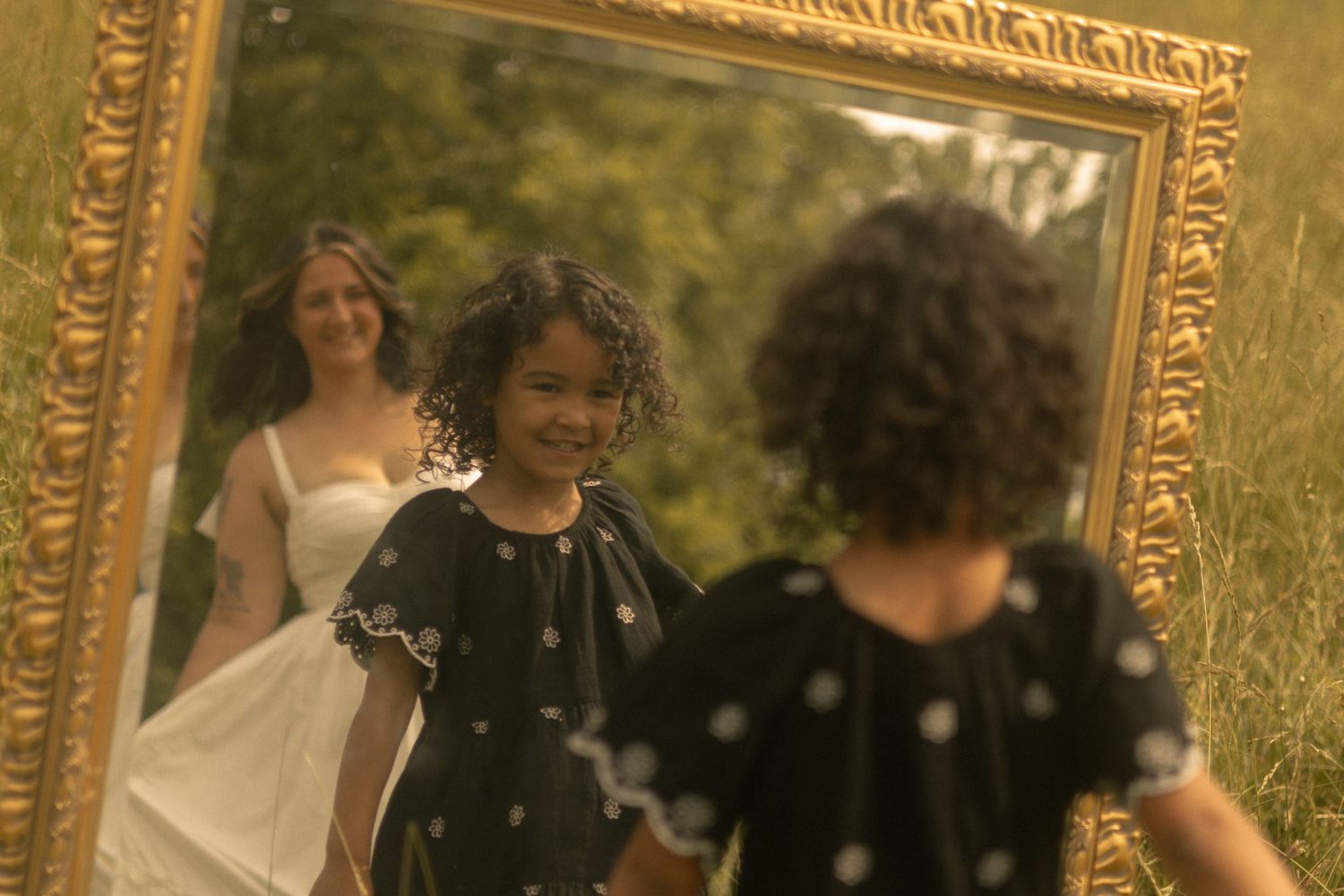 a mother and daughter embrace with love in an outdoor session utilizing a mirror prop for a story telling aspect