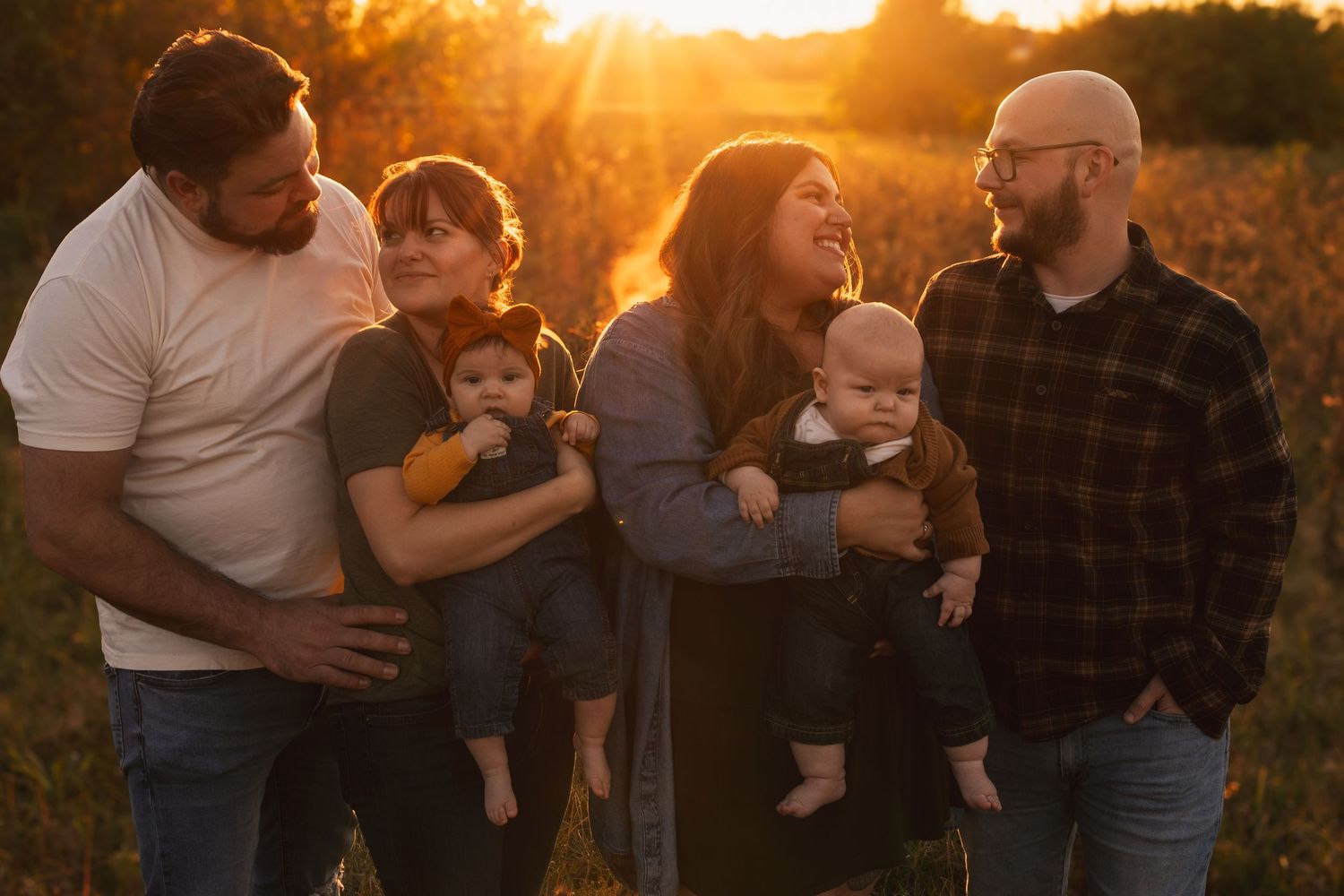 Family gathering outdoors during sunset with golden light filtering through trees.