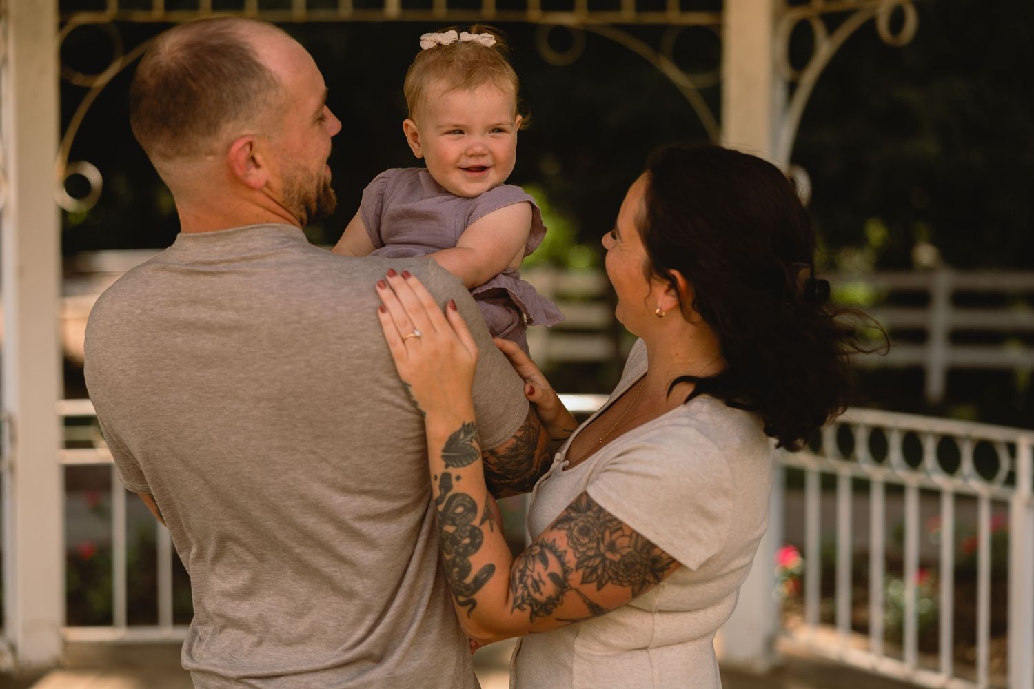 A family shares a joyful moment together on a white gazebo at sunset.
