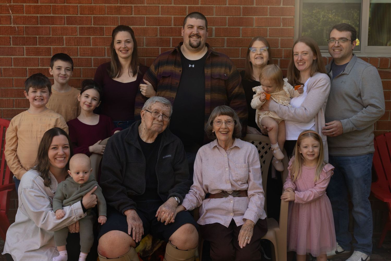 Large extended family gathered together on brick steps for a group portrait.