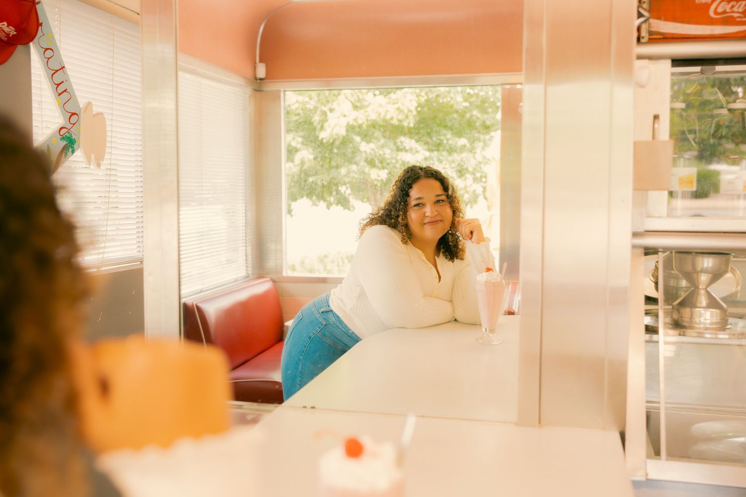 Person relaxing in a vintage diner booth with peach-colored walls.