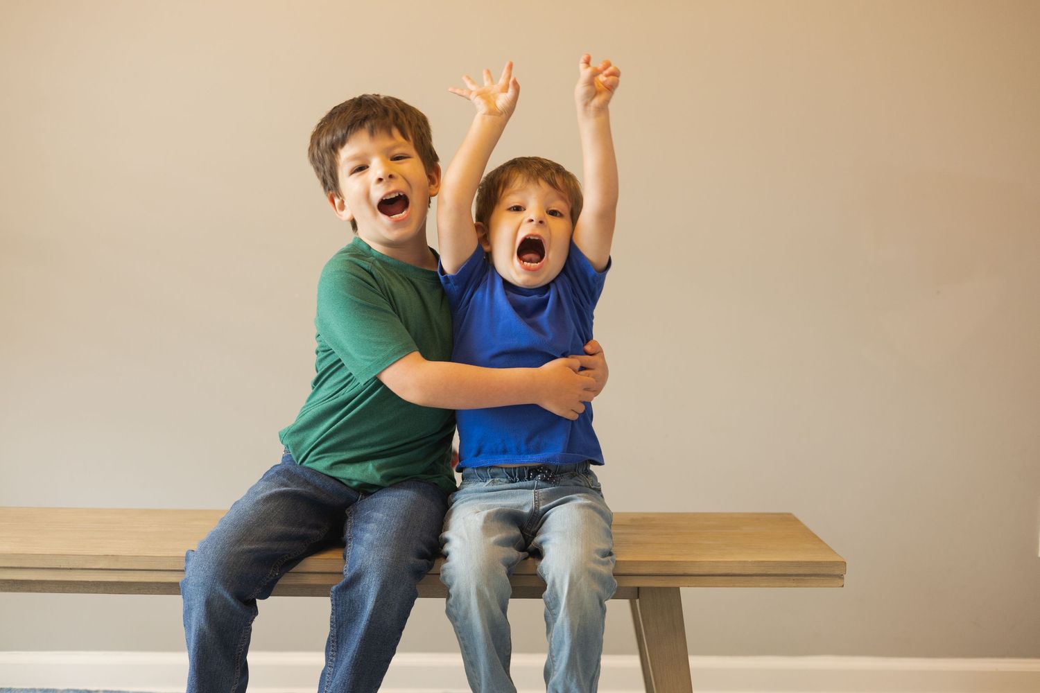Two people sitting together on a bench showing excitement with raised arms.
