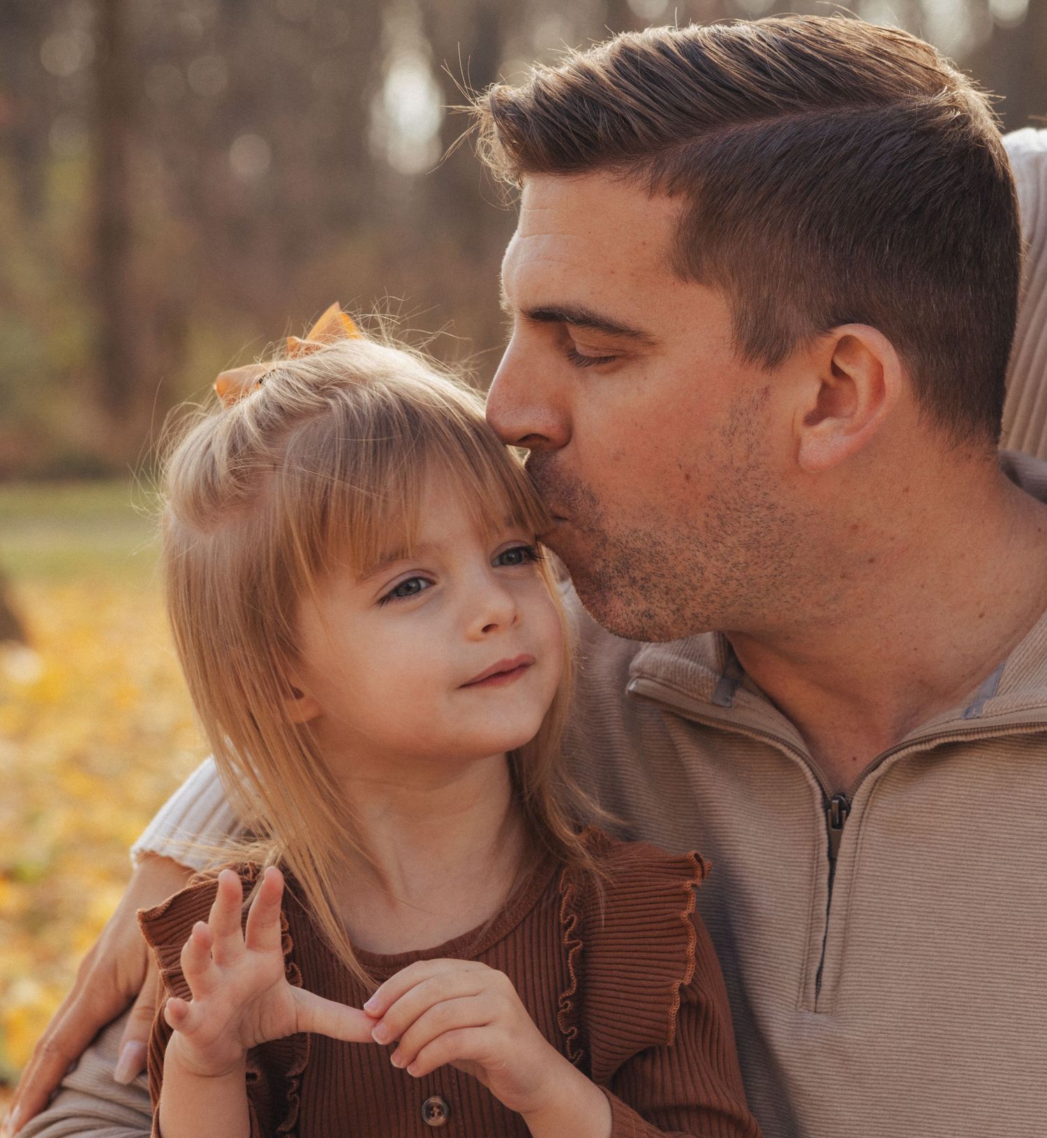 Intimate family portrait captured during golden hour in autumn setting.