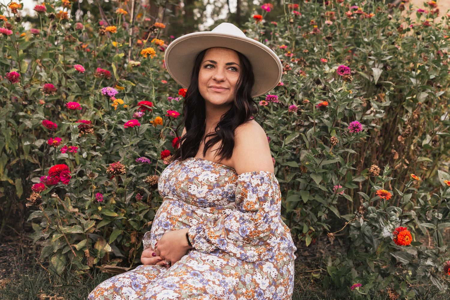 Woman in floral dress standing in a rose garden during sunset.