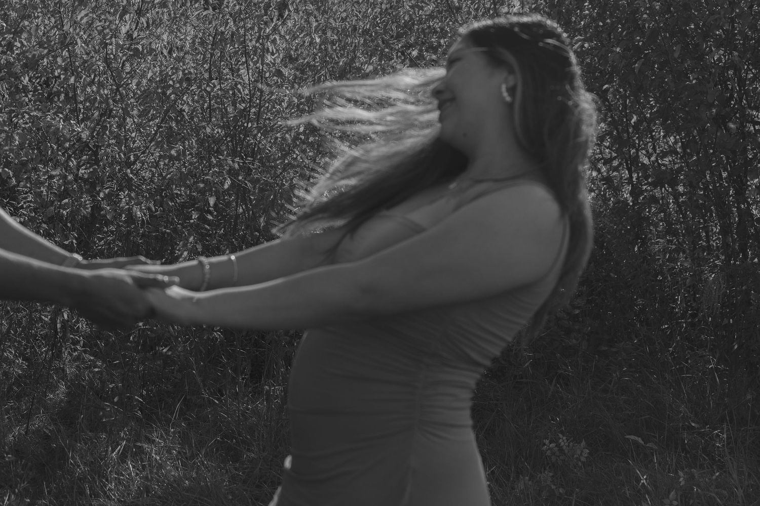 Black and white silhouette of pregnant woman against dramatic lighting.