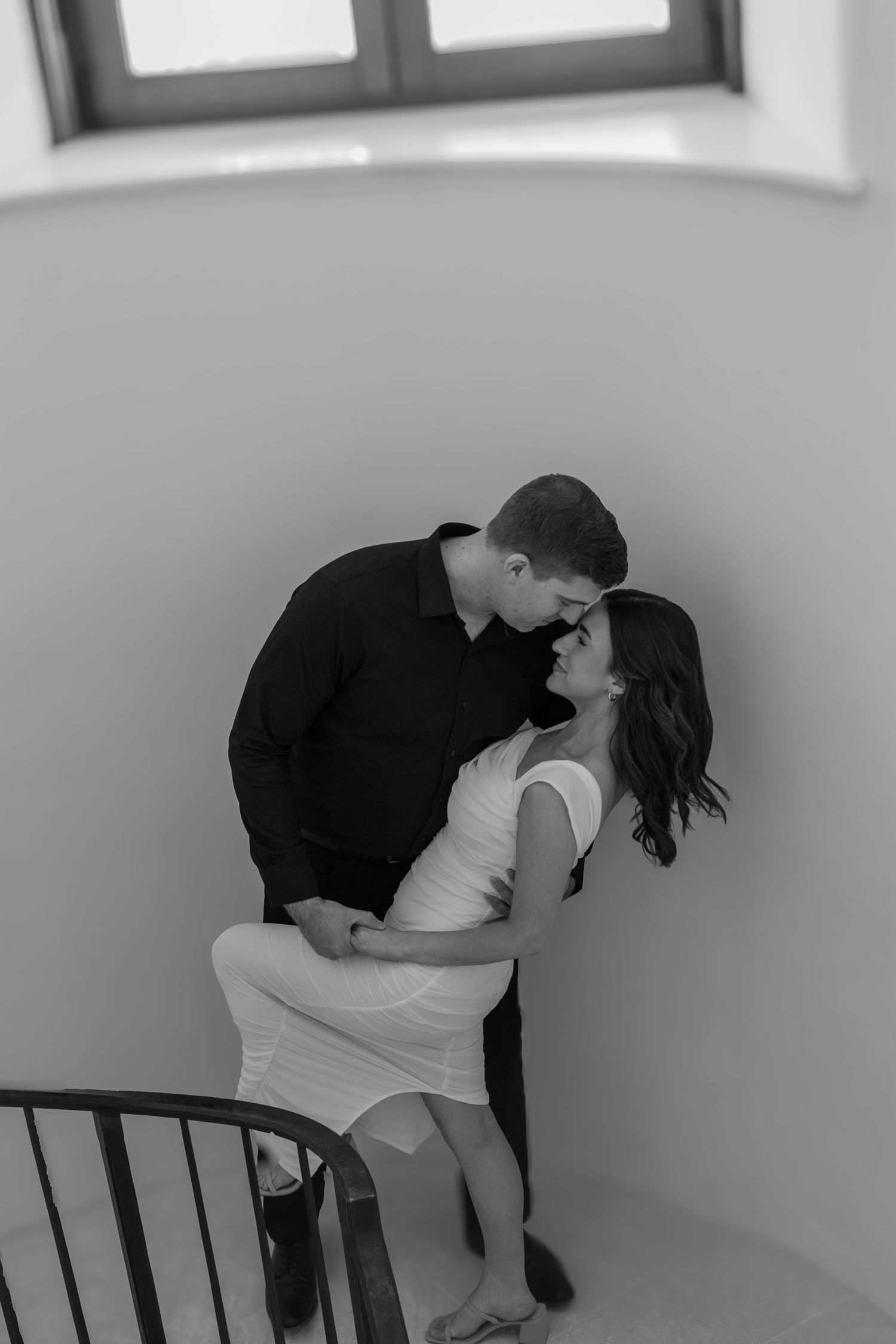 Dancing couple creates romantic poses against a minimalist white wall and bench.