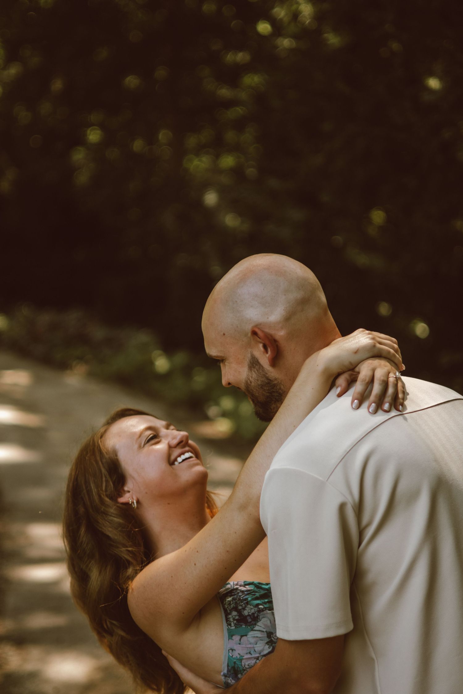 A tender romantic moment captured between two people in dappled sunlight.