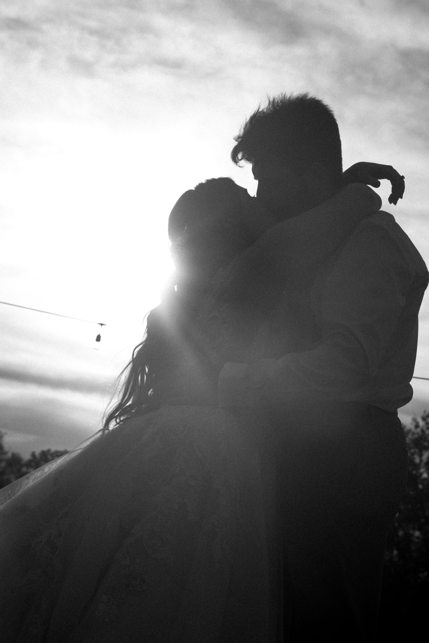 Romantic silhouettes against a dramatic cloudy sky during sunset.