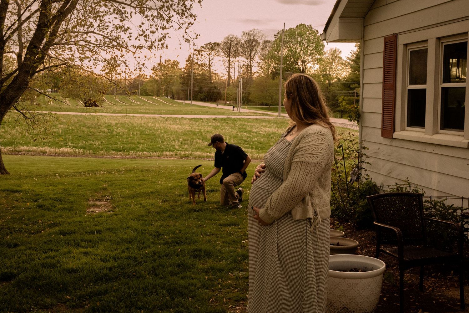 Maternity photo session outside rustic farmhouse with beautiful sunset lighting.