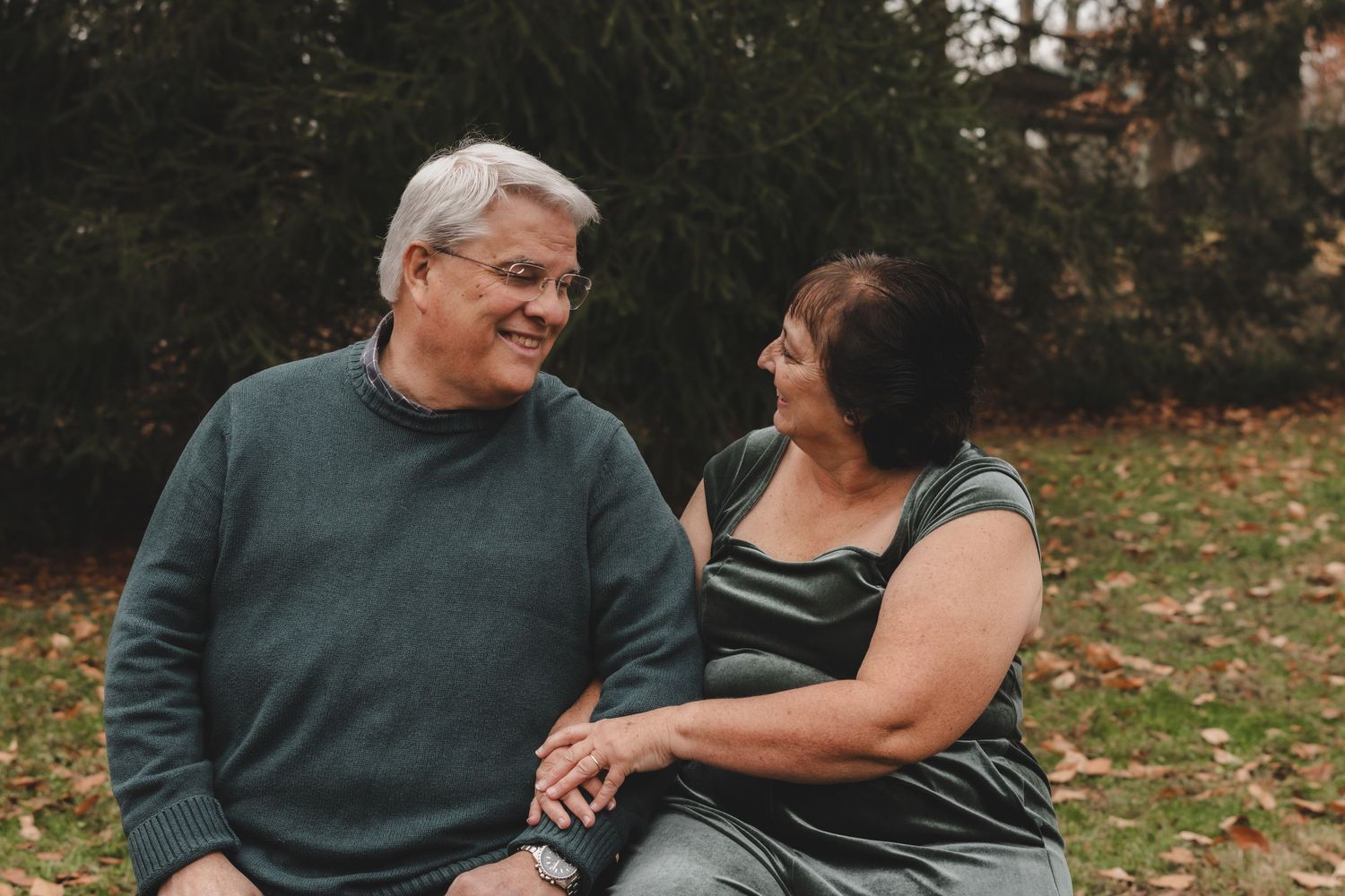 Loving couple shares intimate moment on park bench surrounded by autumn scenery.