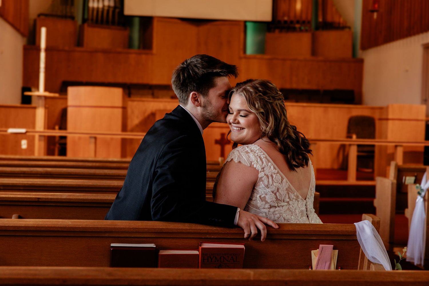 Intimate wedding moment captured in warm light inside a church sanctuary.