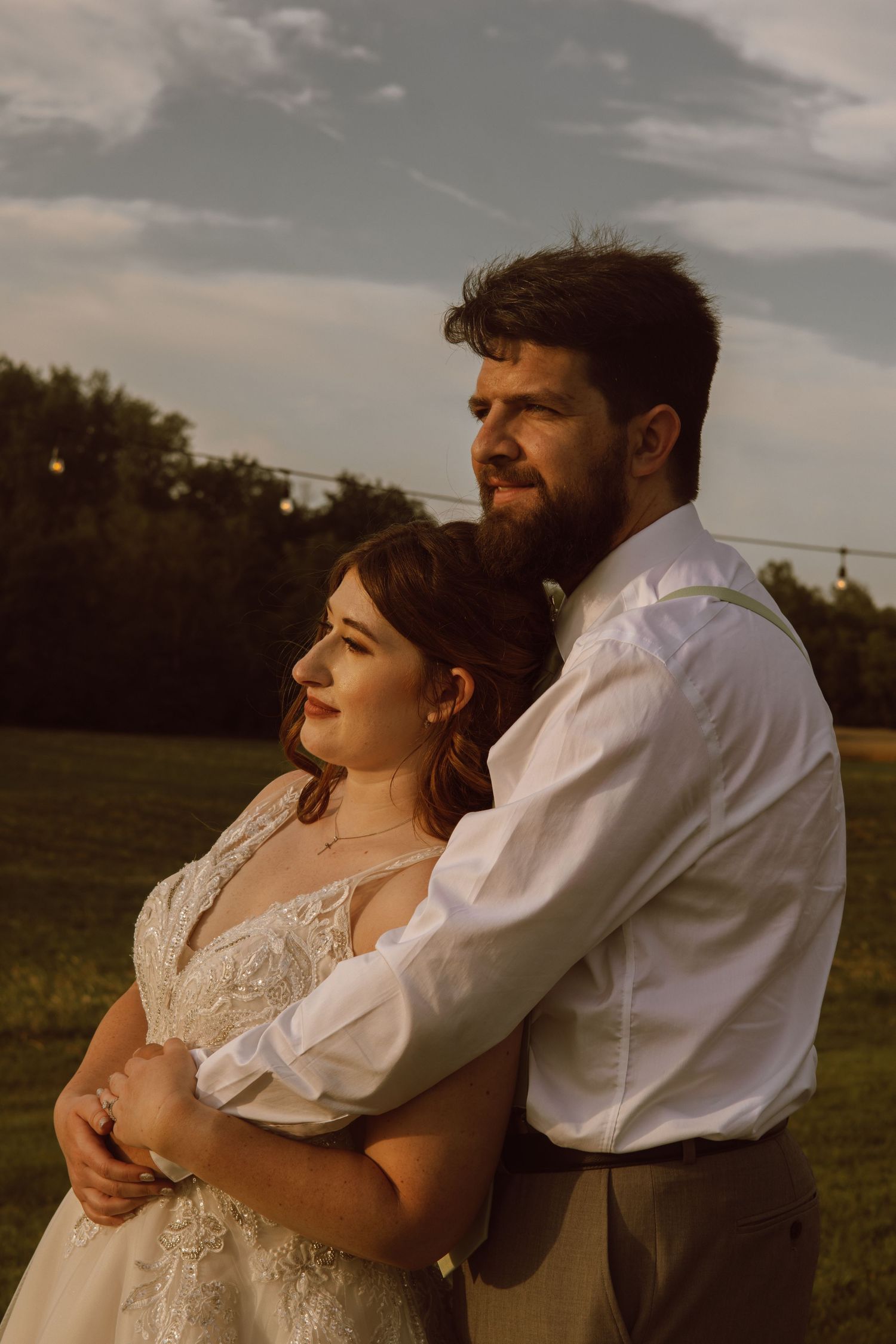 Golden hour portraits of newlyweds embracing in a grassy field.