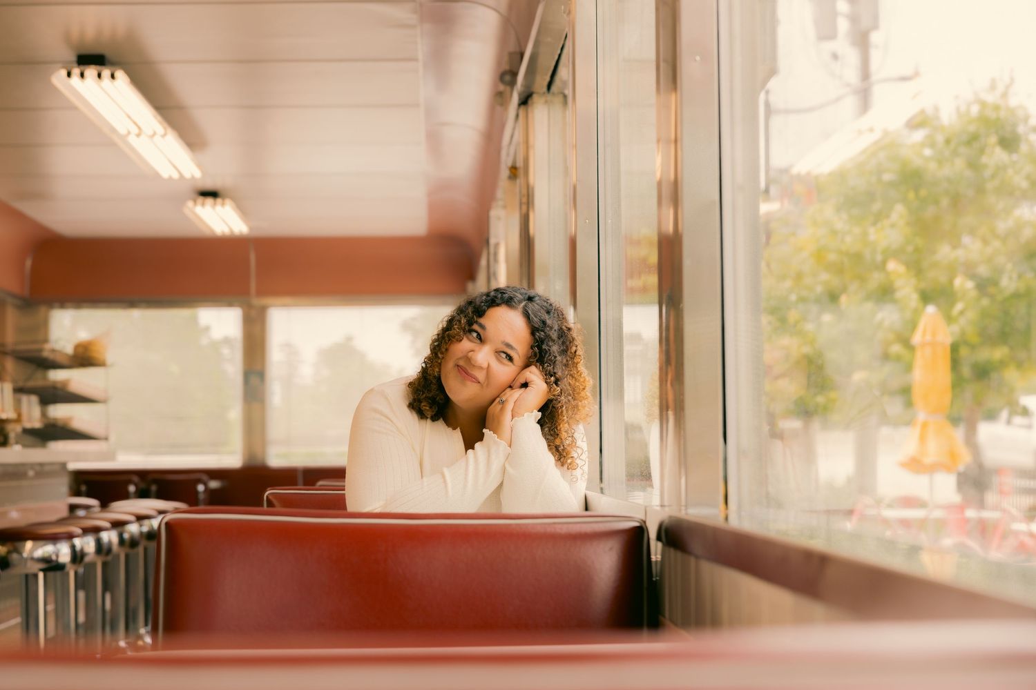 Person resting head on hand while seated in retro diner booth.