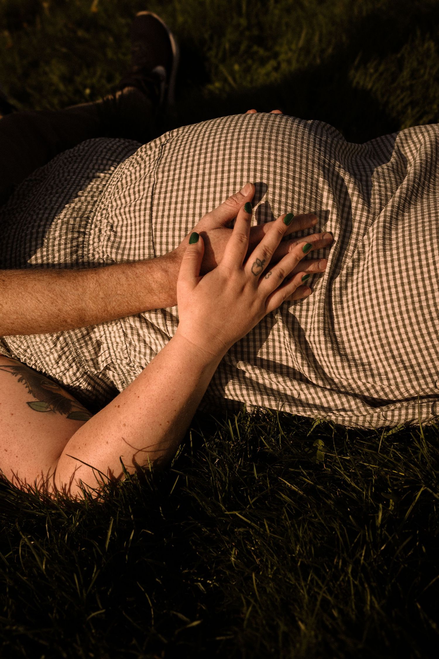 Artistic photo of hands resting on gingham fabric in natural sunlight.
