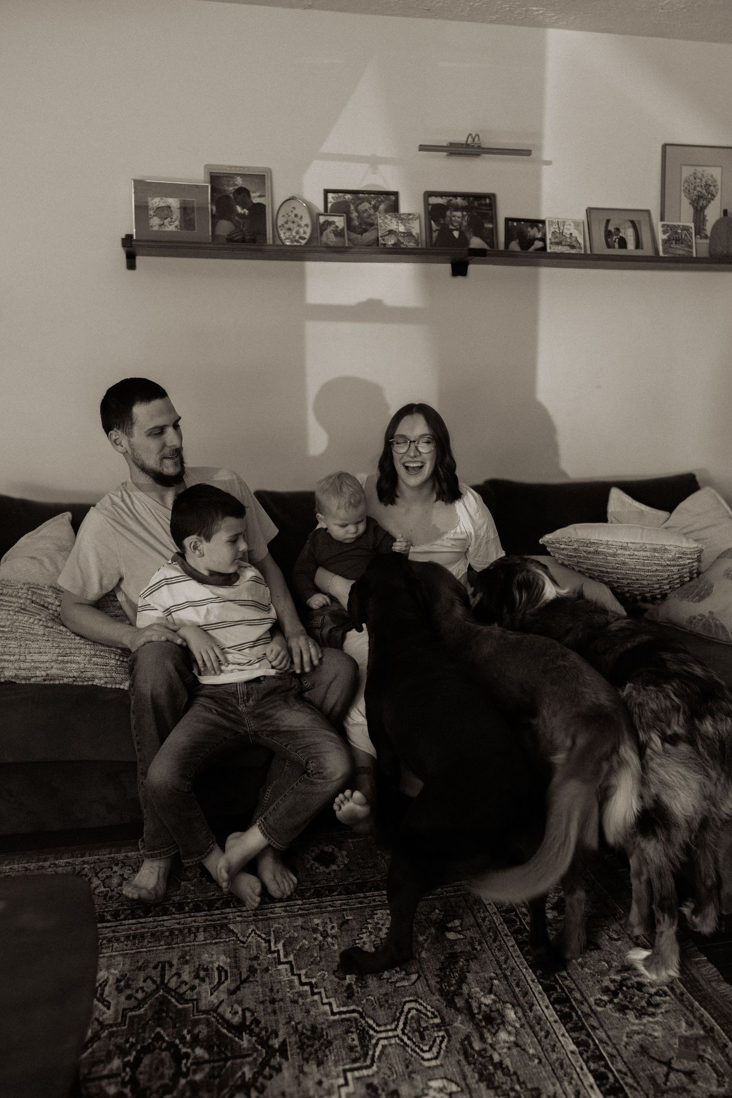 Black and white photo series showing a playful interaction between children and adults on a patterned rug.