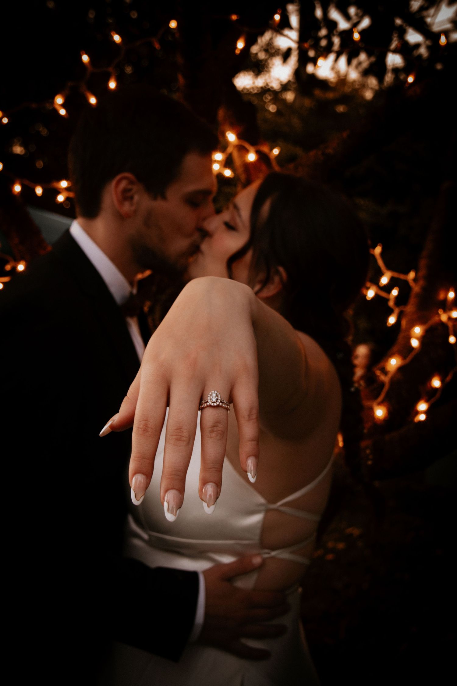 Close-up of romantic wedding moment with sparkly lights and engagement ring detail.