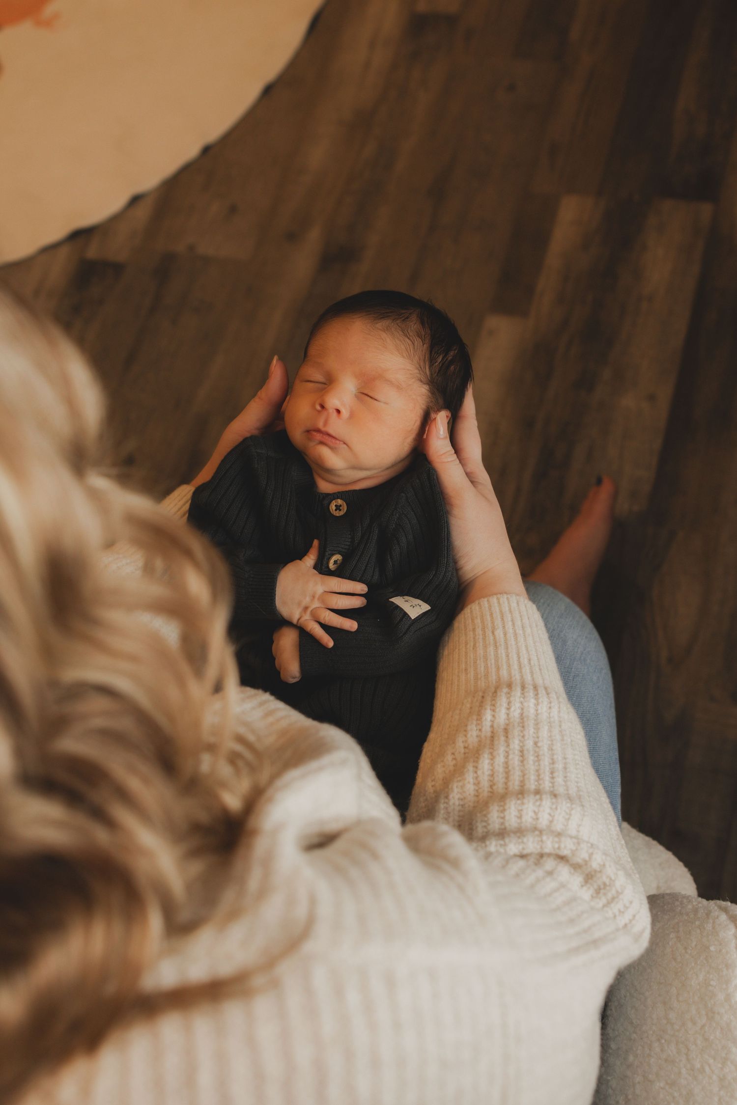 A peaceful newborn baby rests while being cradled in white knit fabric.