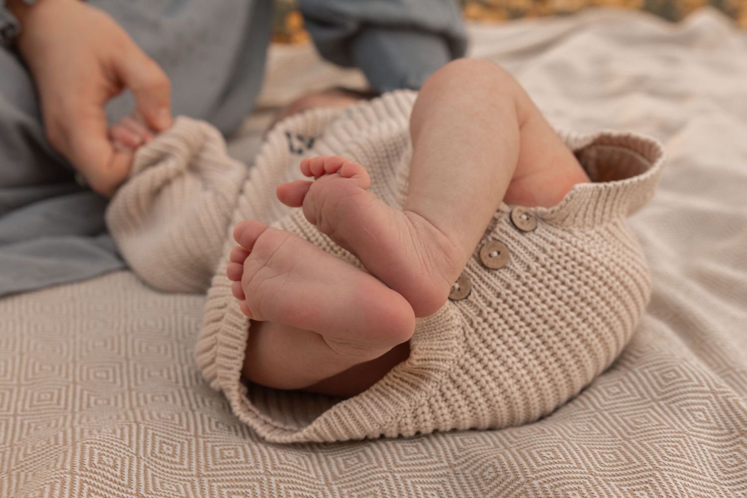 Tiny newborn feet wrapped in soft knit blanket during lifestyle photography session.