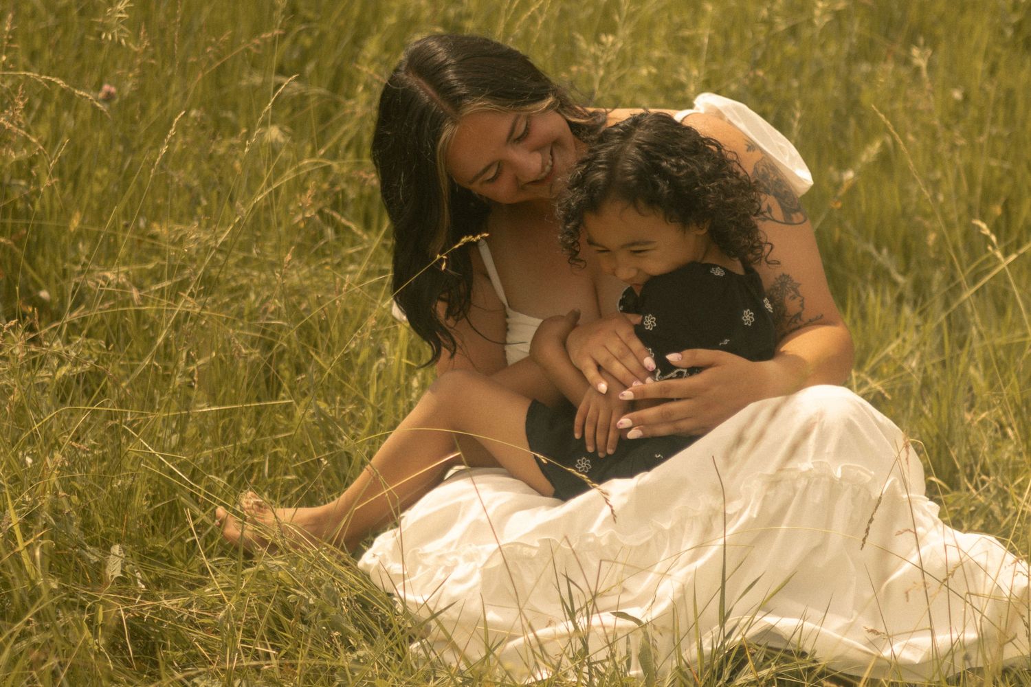 a mother and daughter embrace with love in an outdoor session utilizing a mirror prop for a story telling aspect